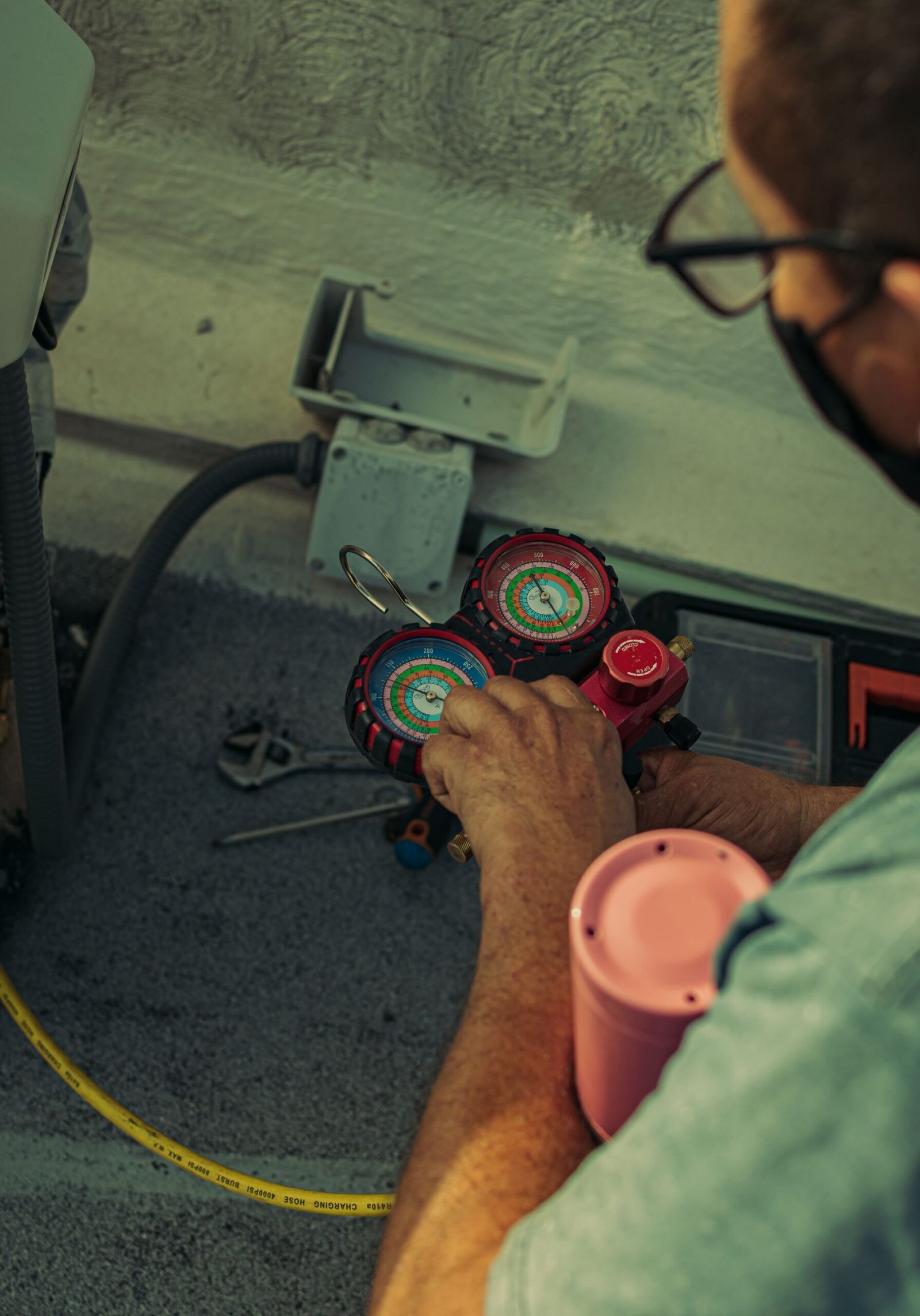 AC technician checking refrigerant gauges on an outdoor unit in Dubai