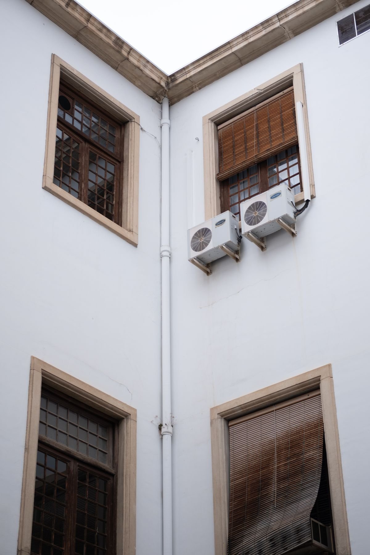 AC units on the corner of a building with wooden blinds