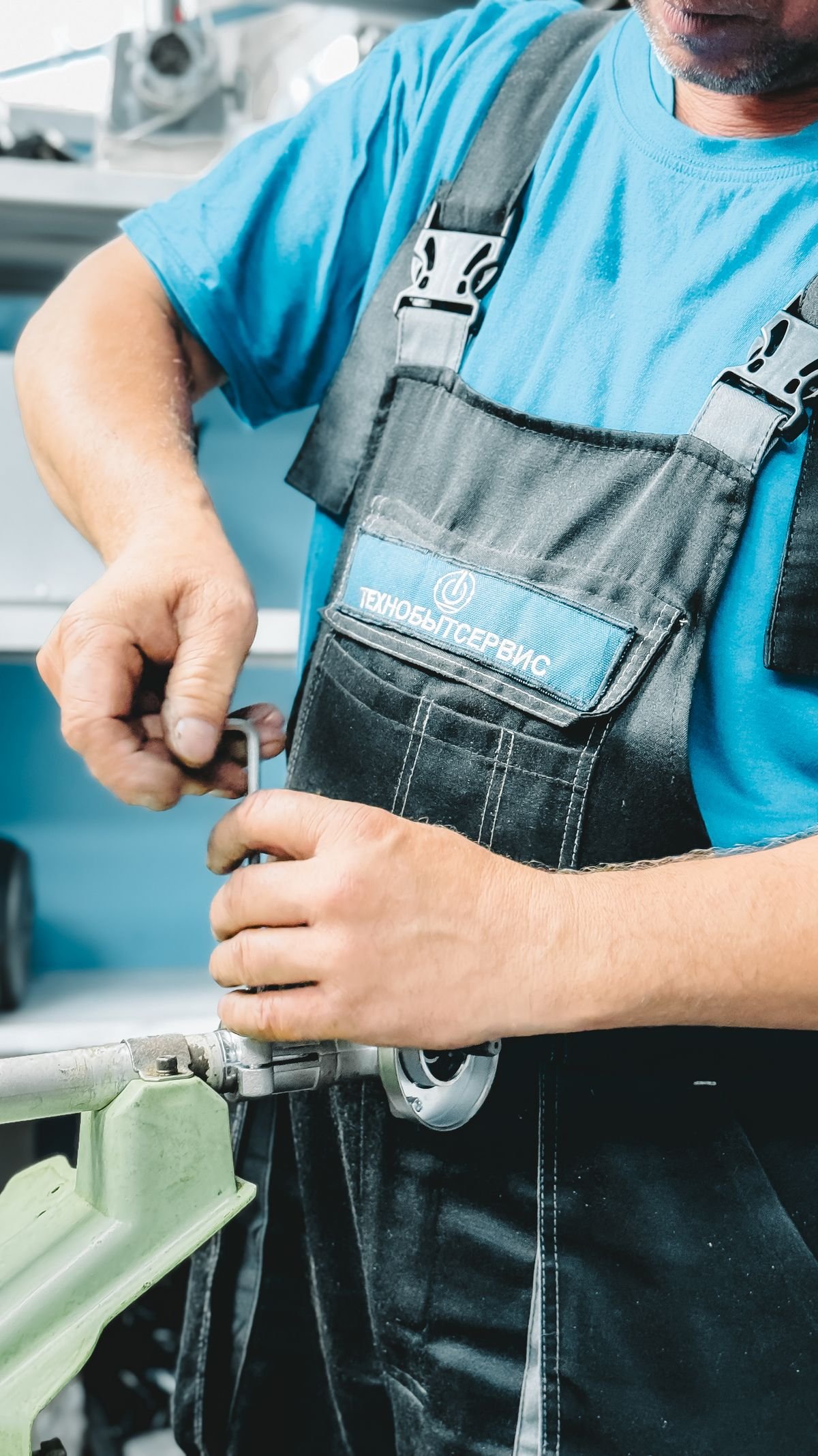 Plumber in blue uniform working on a pipe repair with a wrench