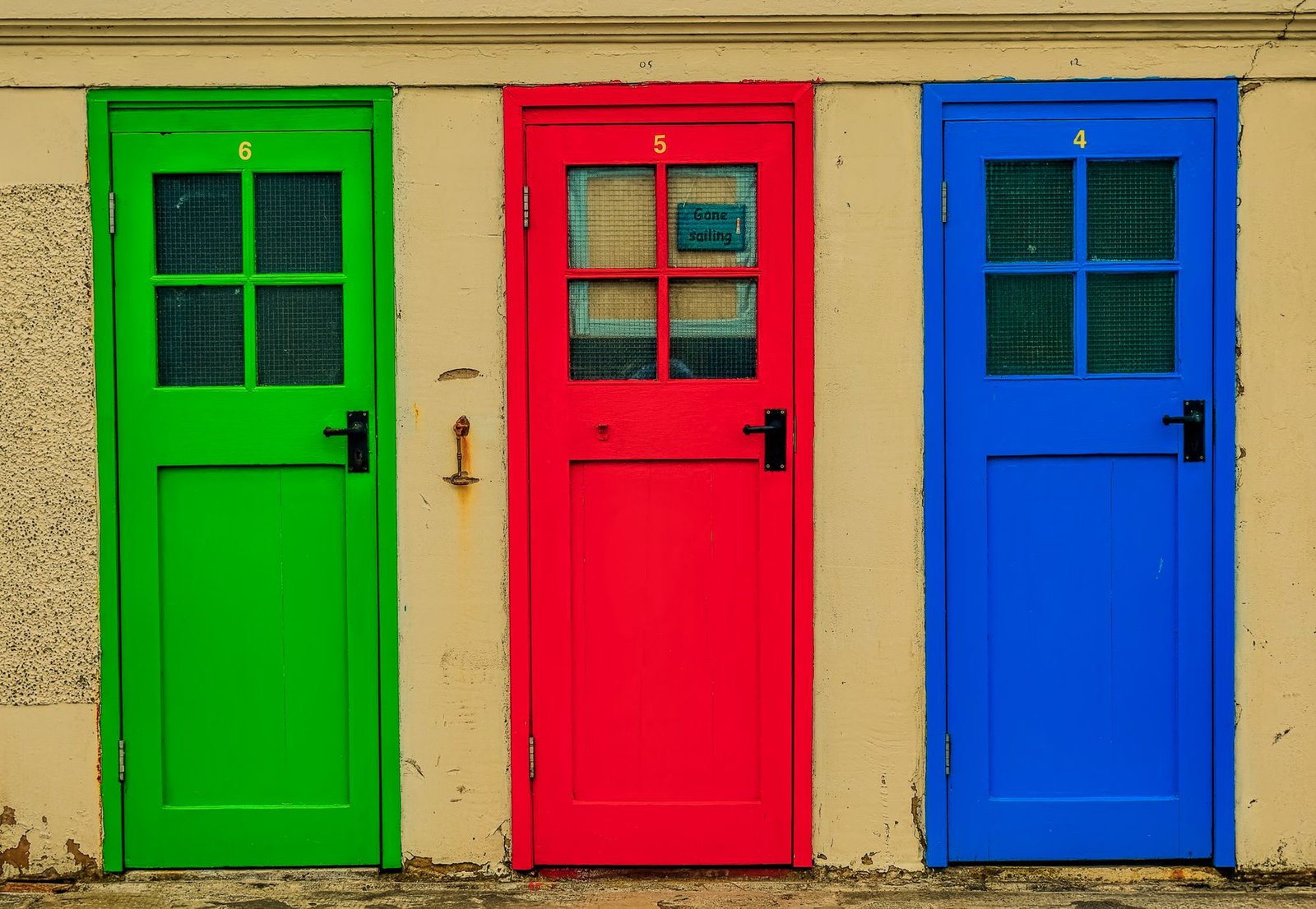 Three freshly painted doors in green, red, and blue side by side