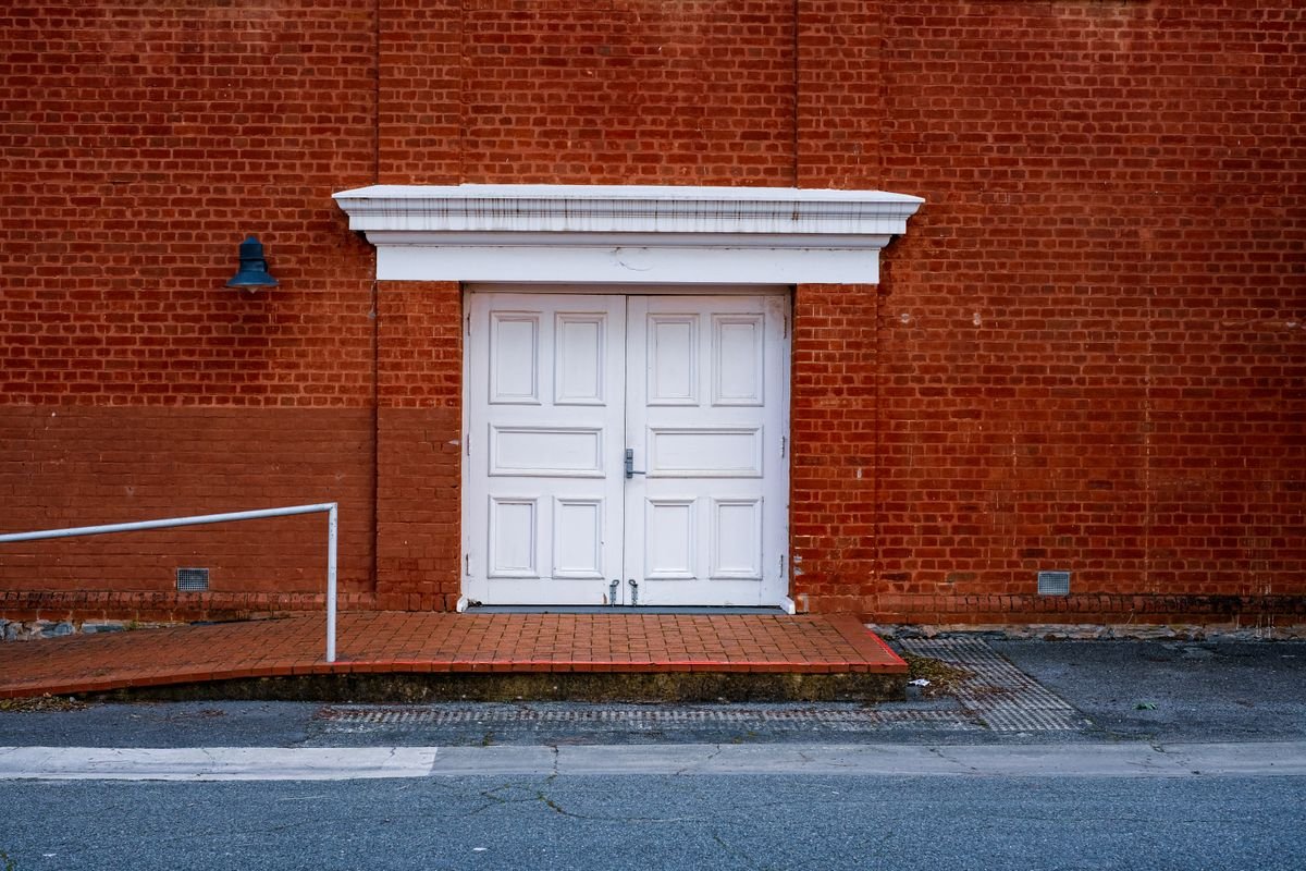 Clean white entrance doors set in a red brick wall
