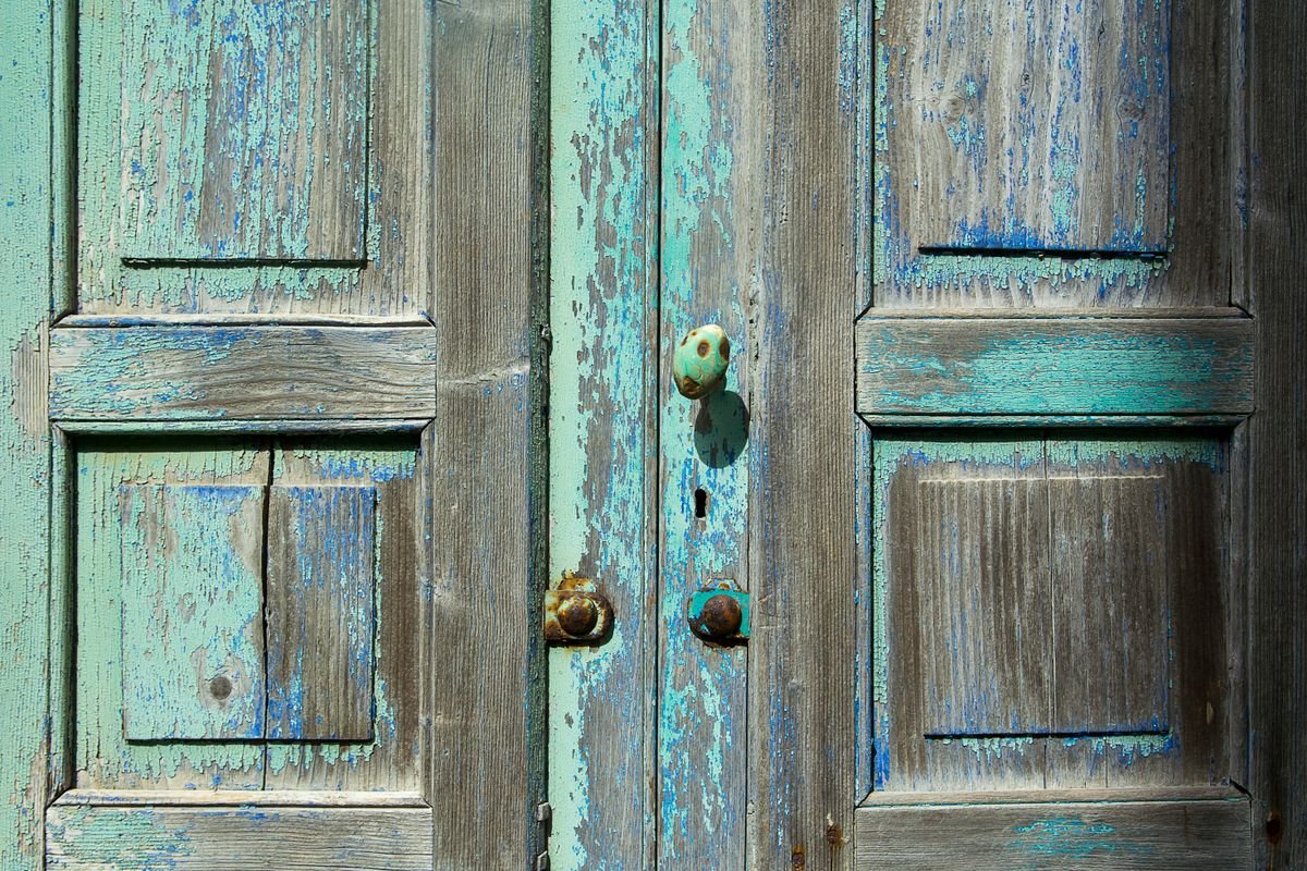 Weathered wooden door with peeling blue and turquoise paint