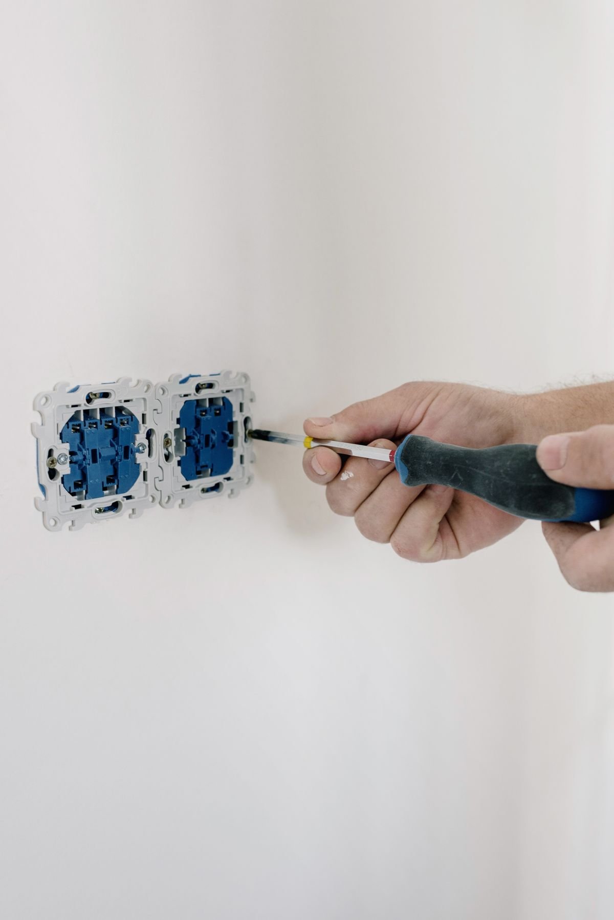 Electrician using a screwdriver to install switches in an apartment
