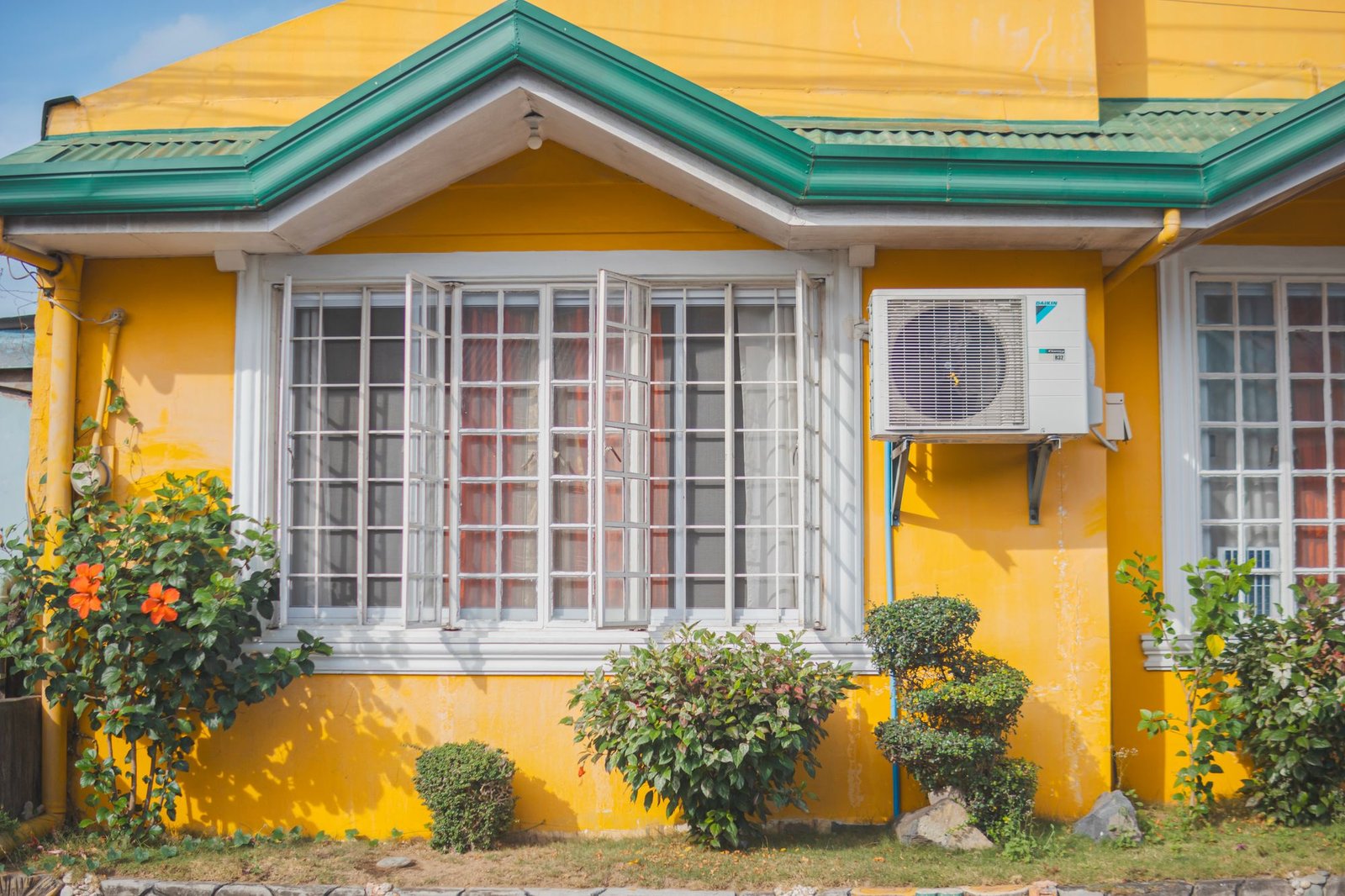 Home exterior with an outdoor AC unit mounted beside a window