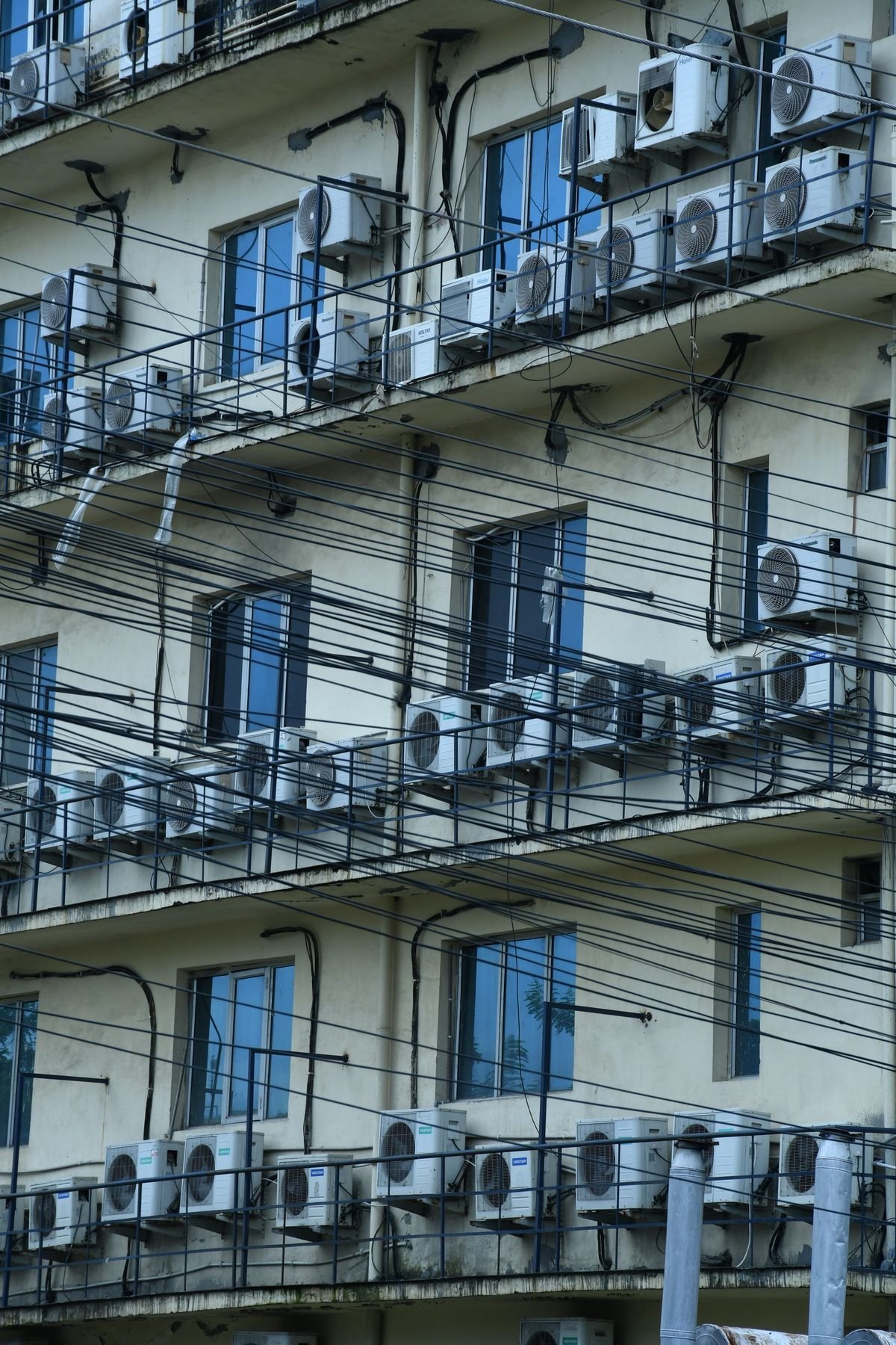 Facade of an urban residential building with multiple air conditioners and balconies
