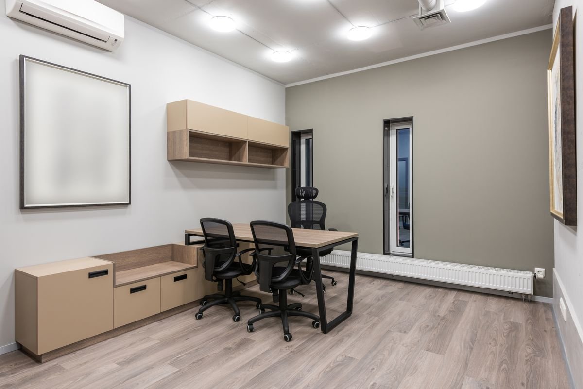 Office with a flat white ceiling, downlights, and desks along the wall