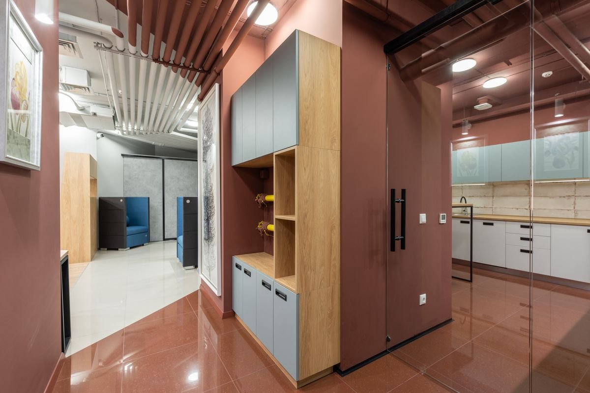 Office with a red-brown feature wall and a slatted ceiling above glass partitions