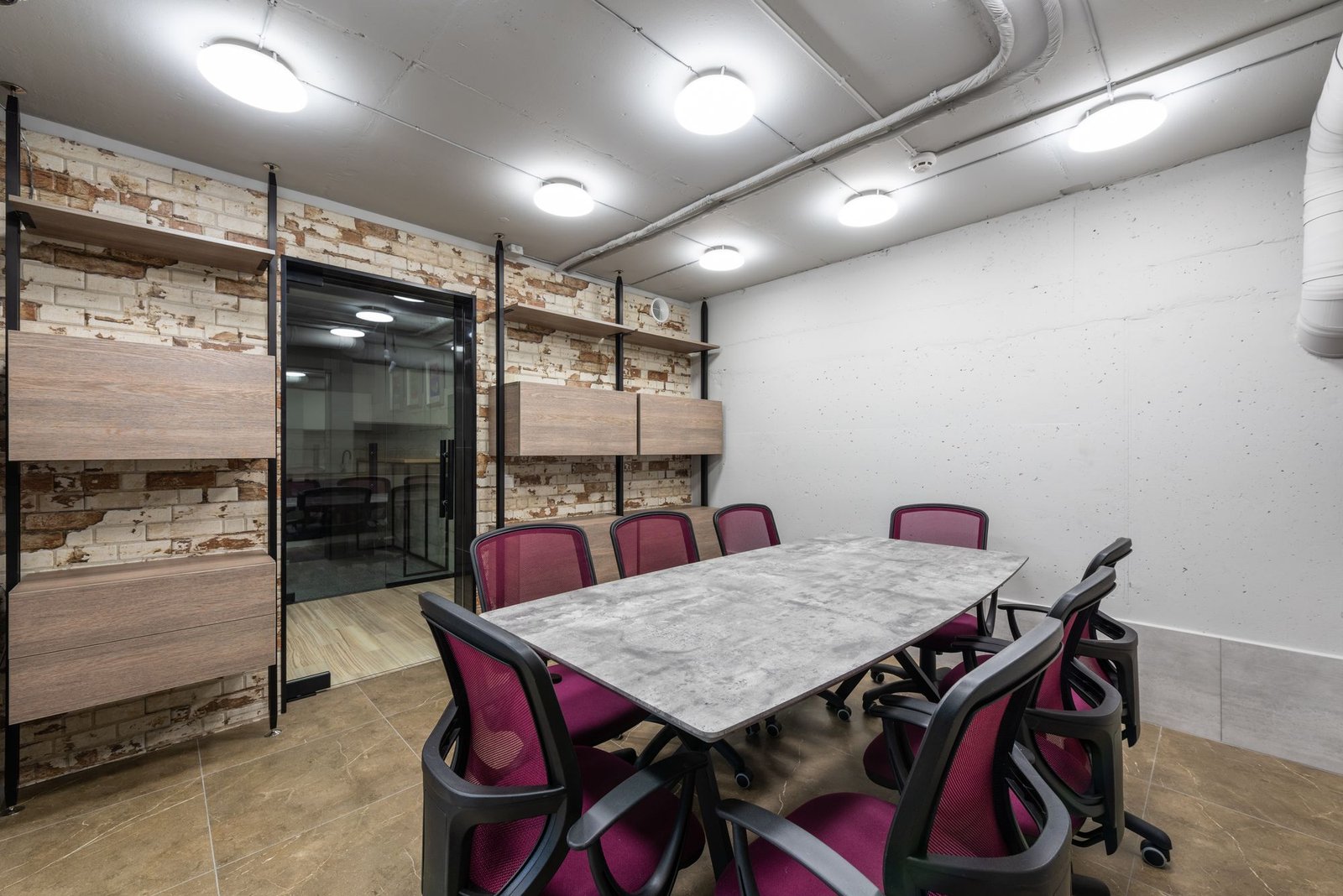 Meeting room with a marble-topped table and burgundy chairs behind black-framed glass partitions