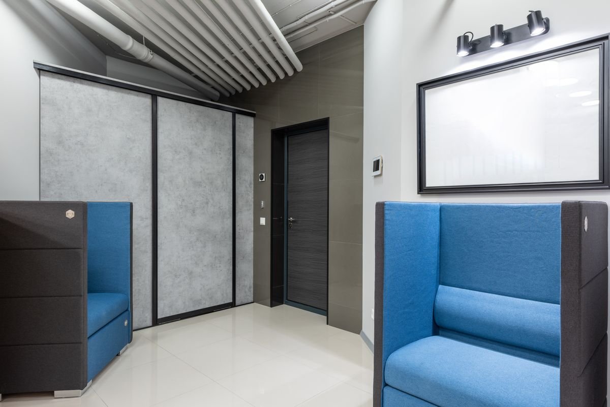 Blue seating pod beside a frosted glass partition and a wall-mounted screen