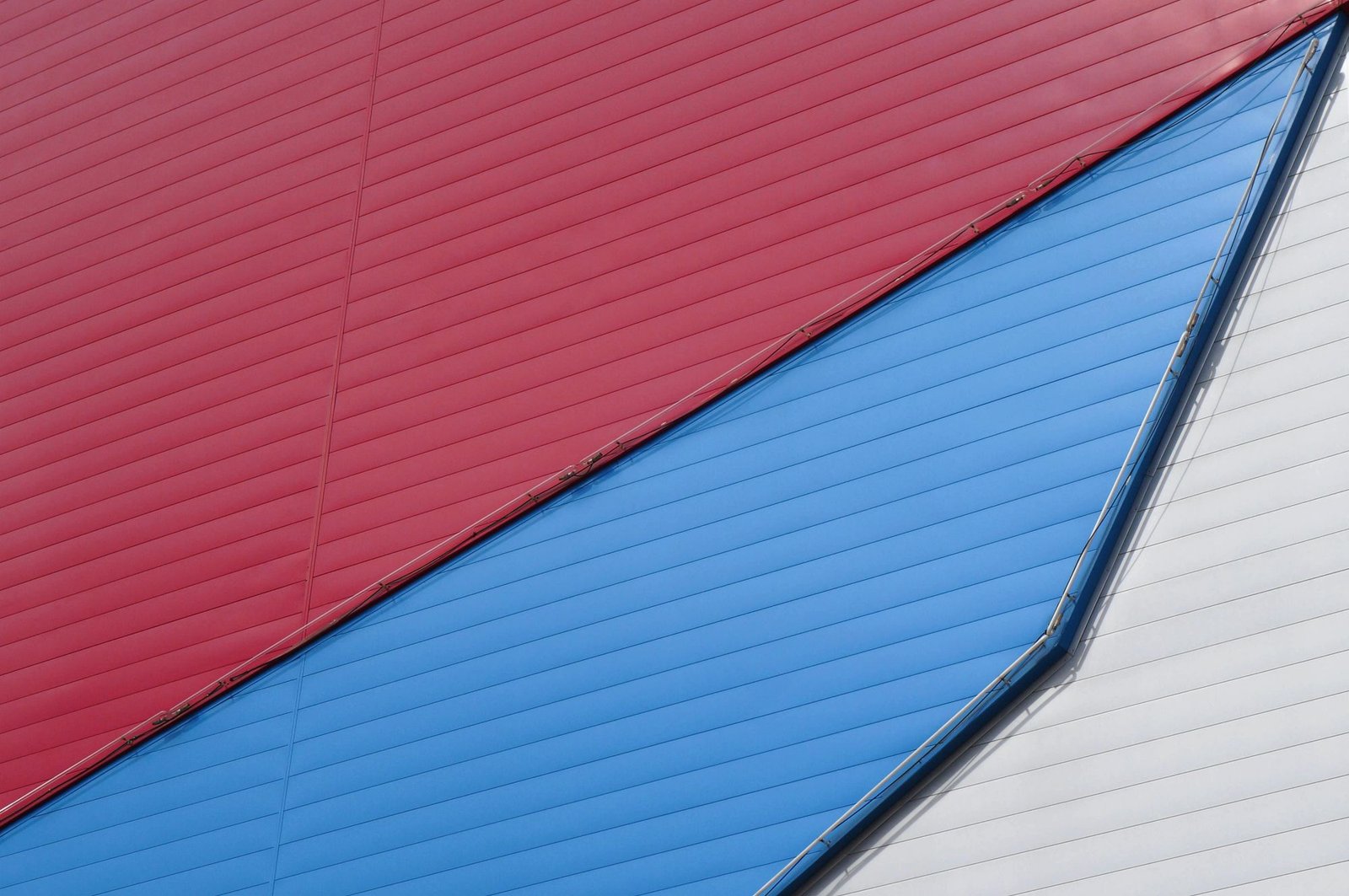 Minimalist building facade with diagonal stripes of red, blue, and white cladding panels