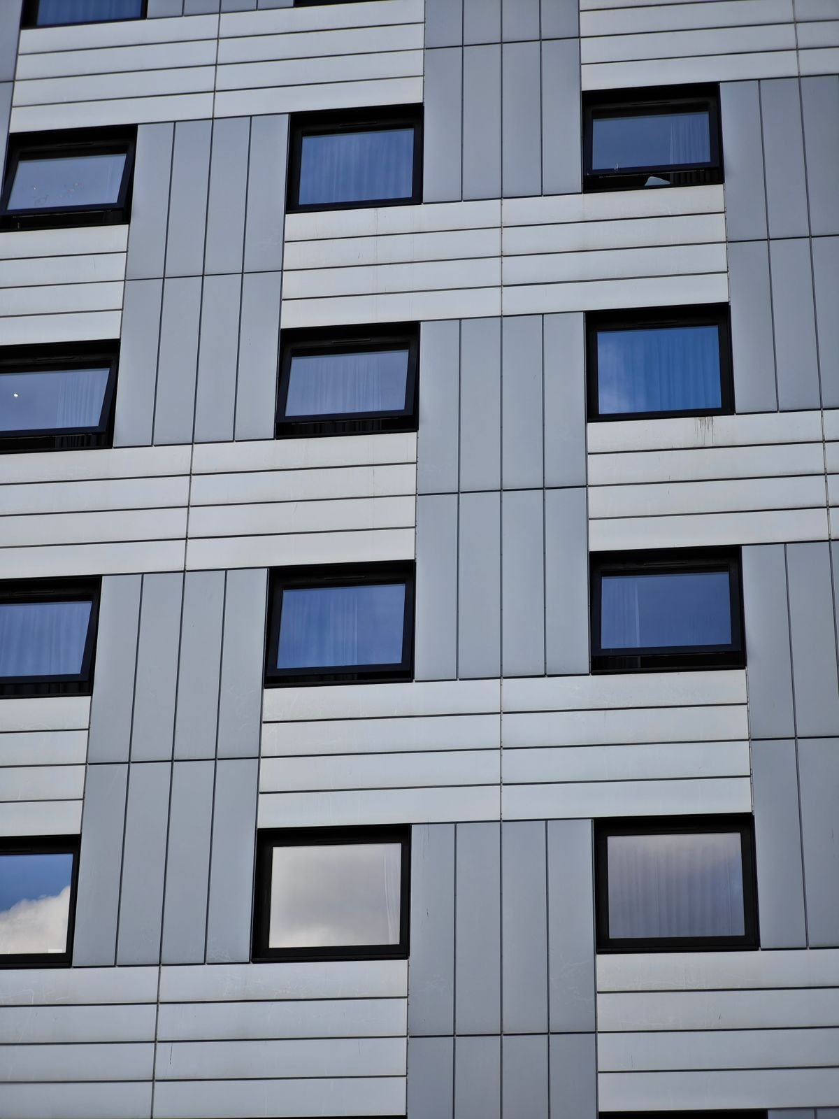 Modern building facade with a geometric pattern of window openings and panels