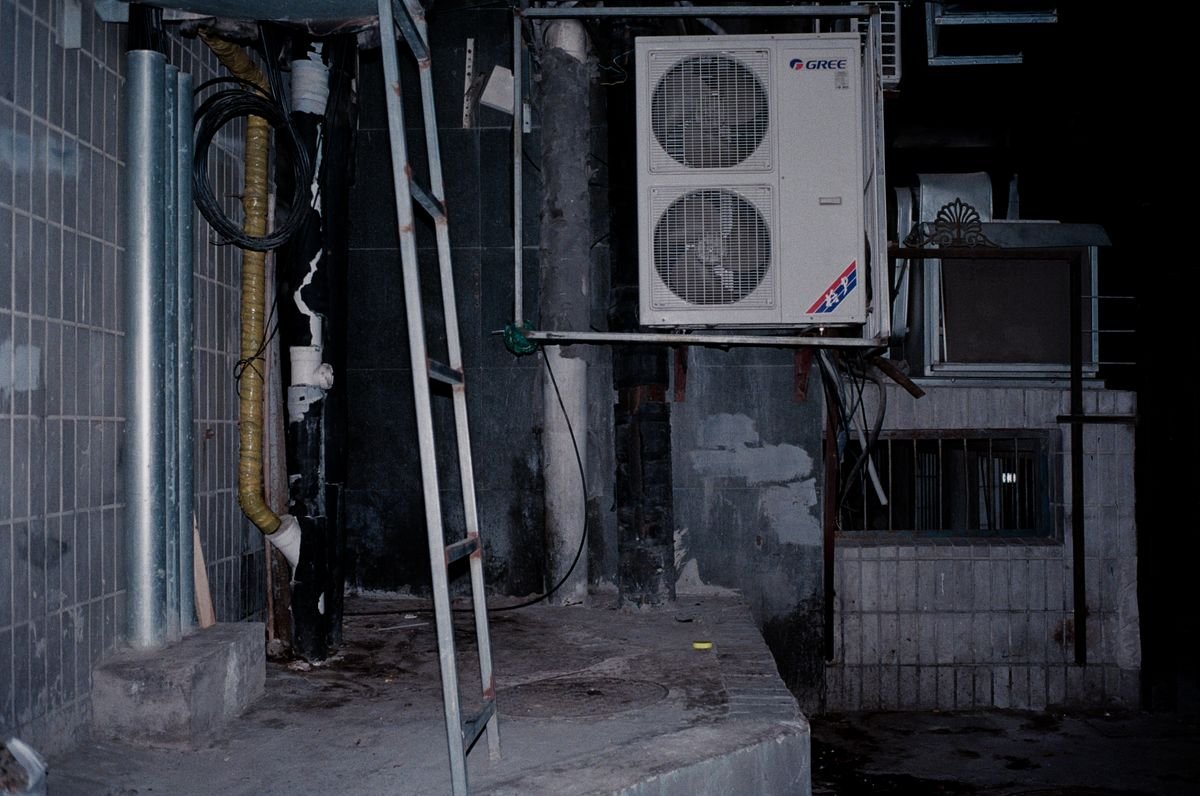 Close-up of an industrial air conditioner setup showing pipes and a ladder
