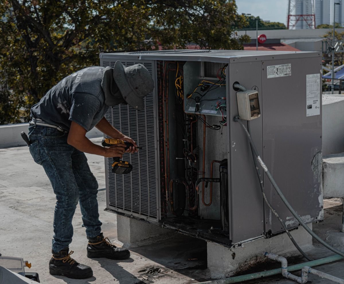 Repairman fixing an air conditioner on a rooftop