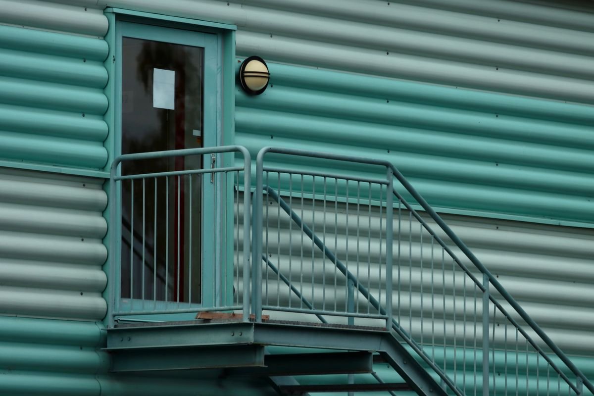 Green industrial building facade with a metal staircase and door