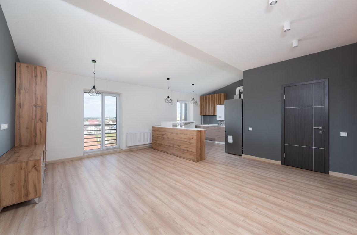 Open-plan apartment with white walls and a dark grey accent wall near the kitchen