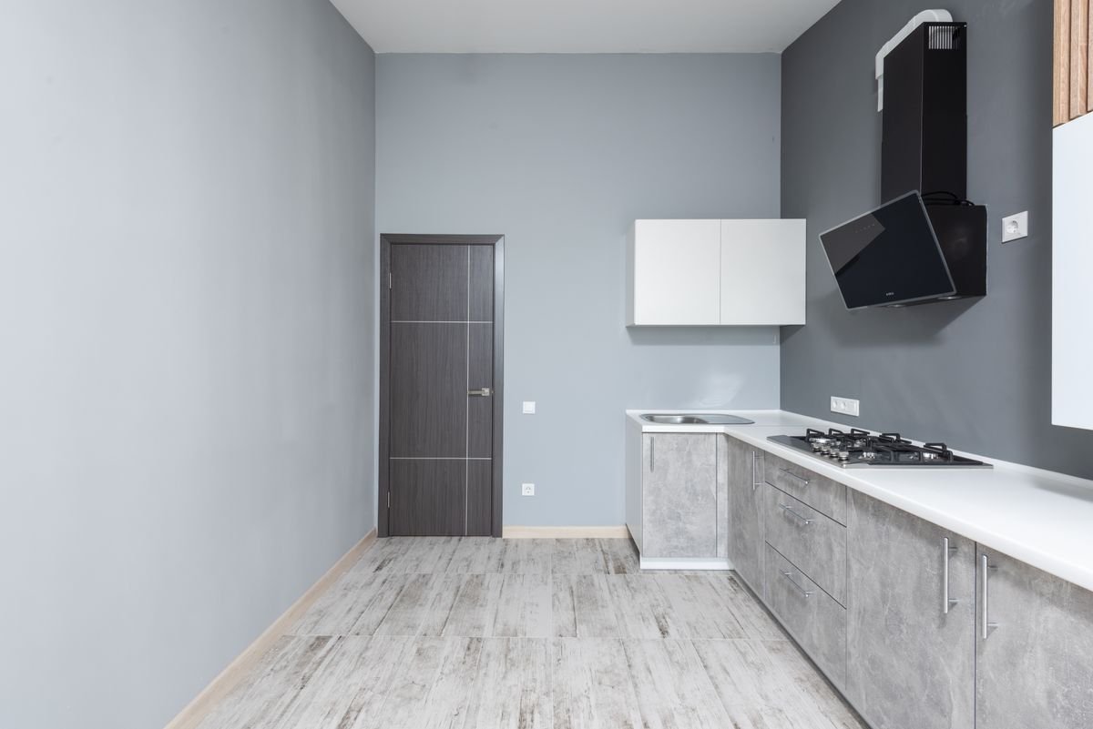 Light grey painted apartment kitchen with wood cabinetry