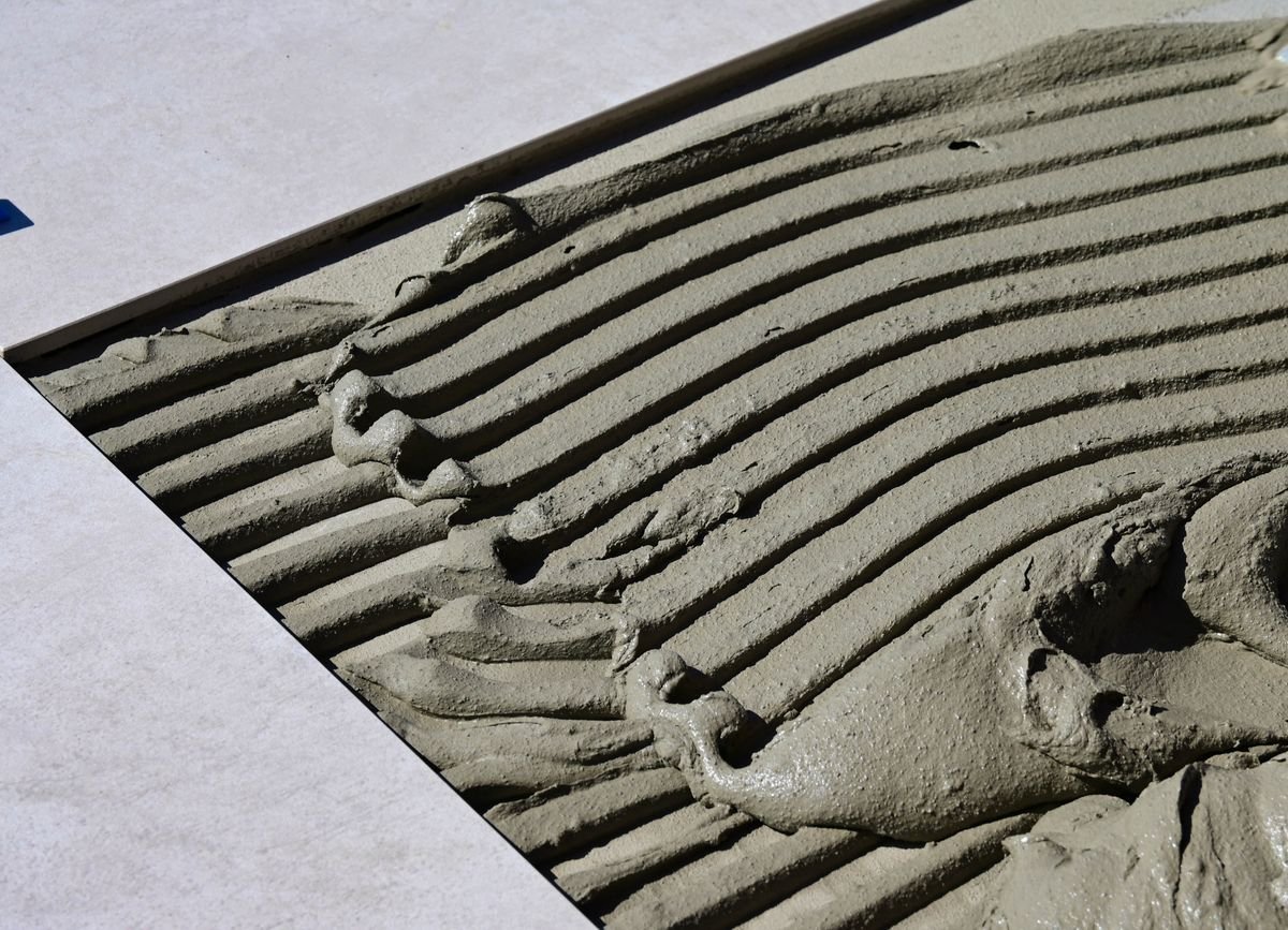 Combed tile adhesive ridges beside a large porcelain tile