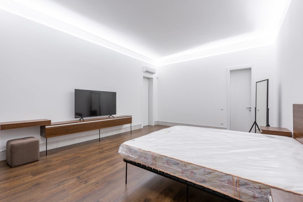 White bedroom with an LED cove running along the false ceiling edge