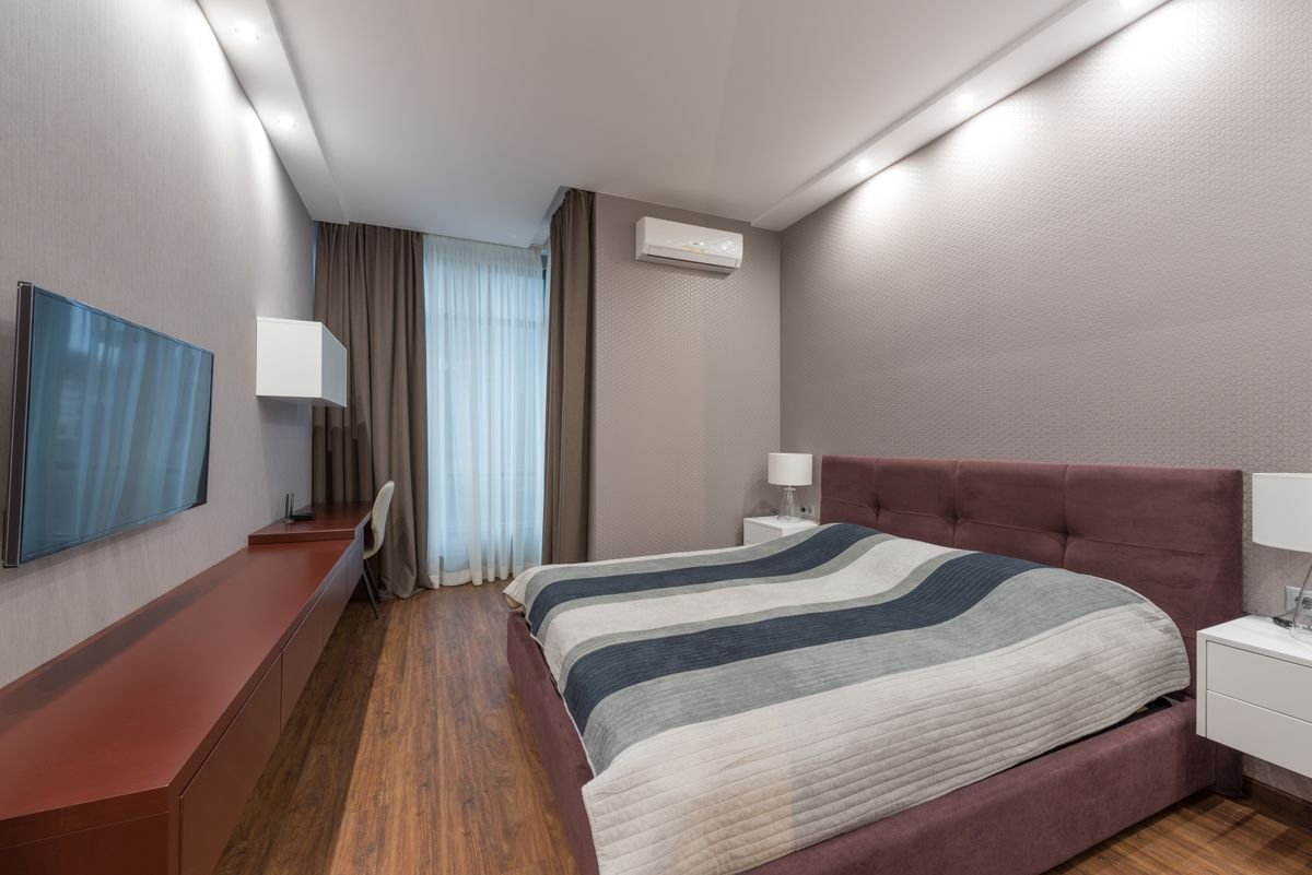 Bedroom with grey walls, a false ceiling with spotlights, and heavy curtains