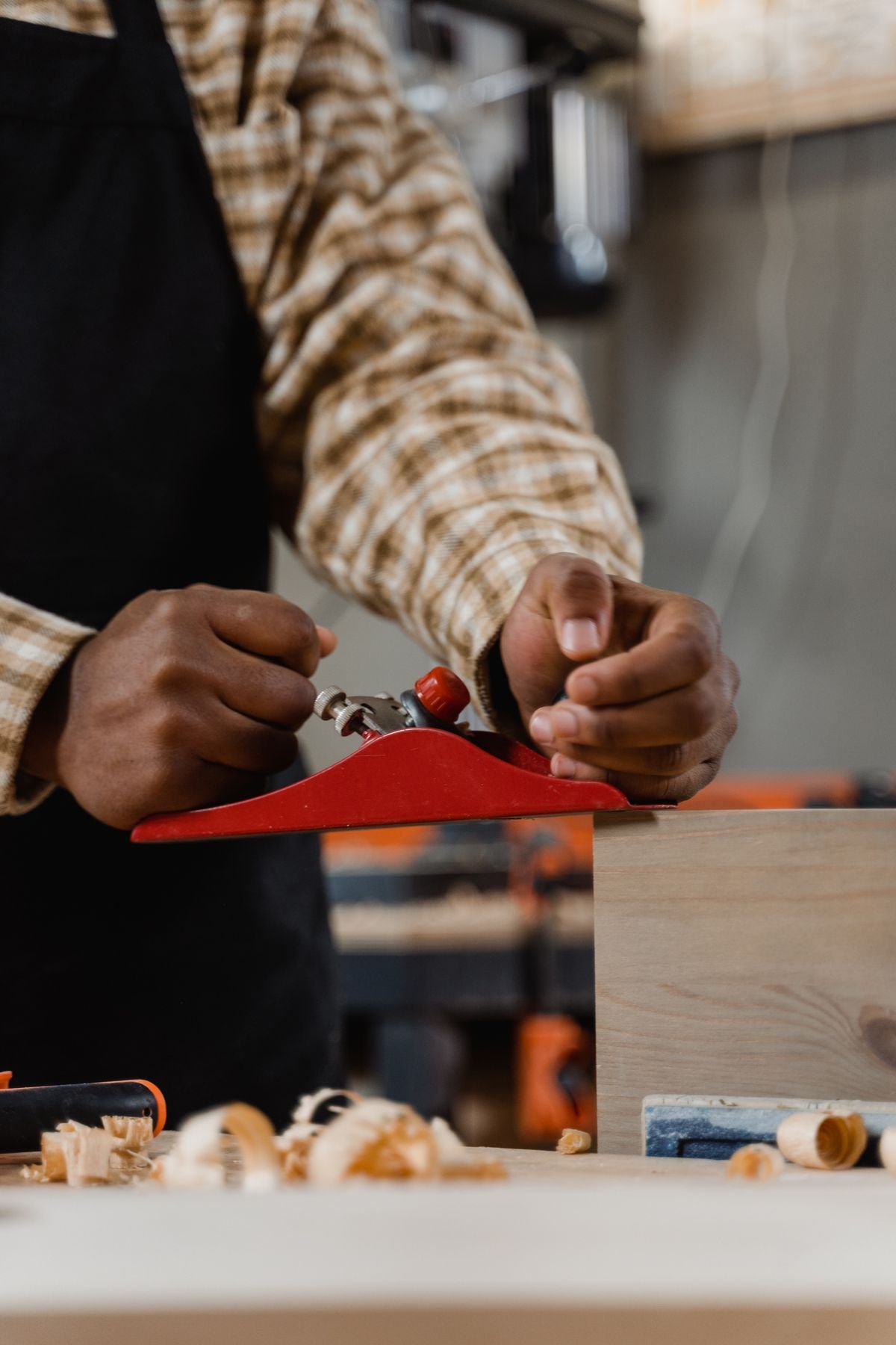 Carpenter smoothing wood with hand plane in a workshop