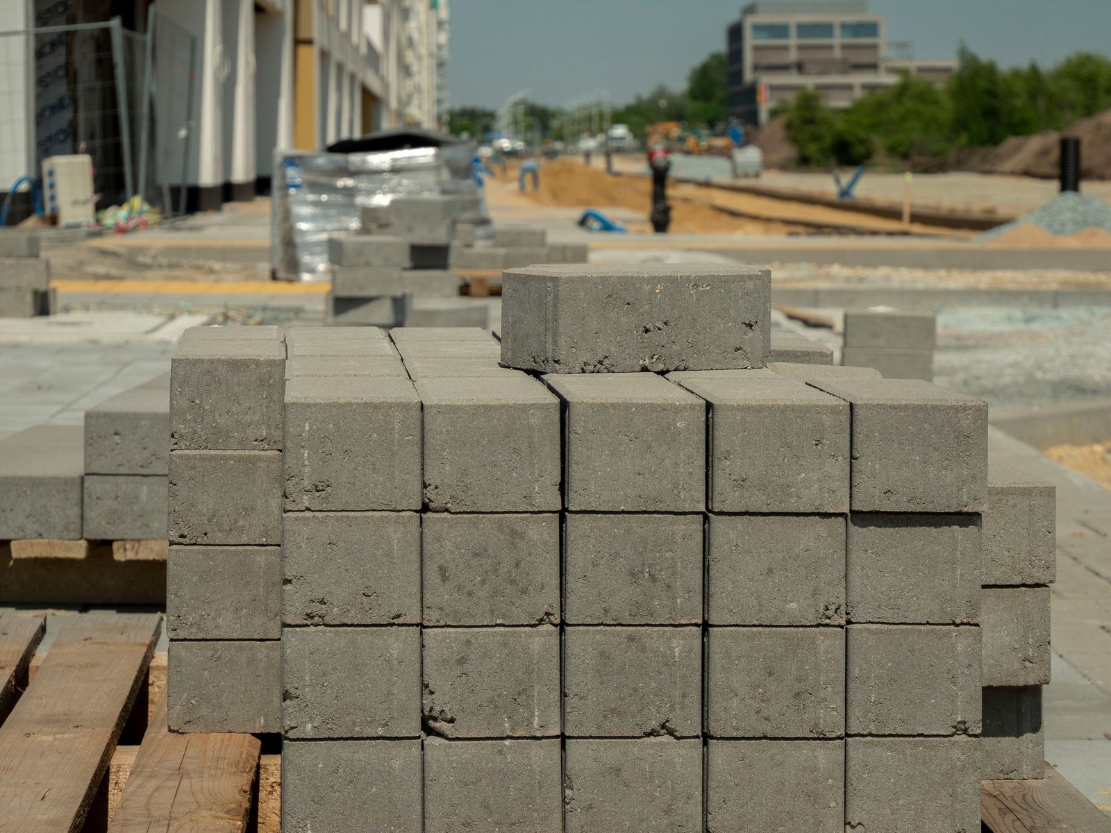 Stack of new grey concrete paver blocks ready for installation at a construction site