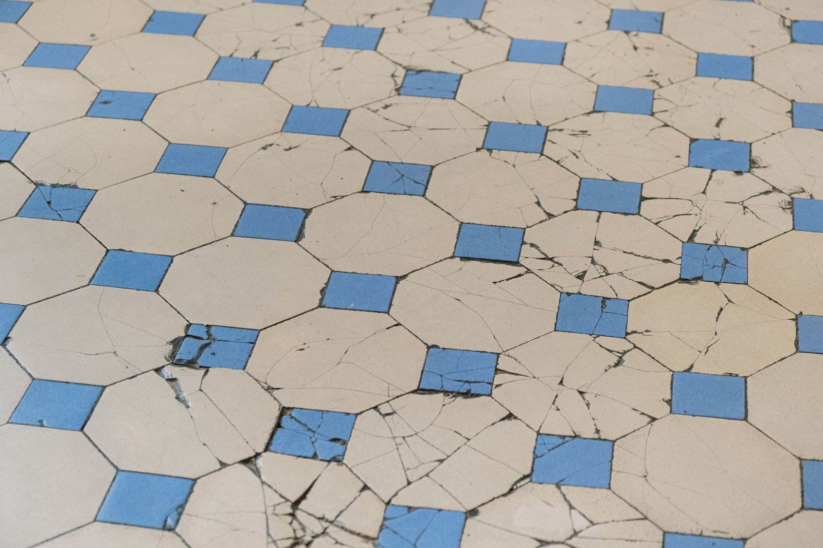Aged cracked blue and white geometric floor tiles in need of replacement
