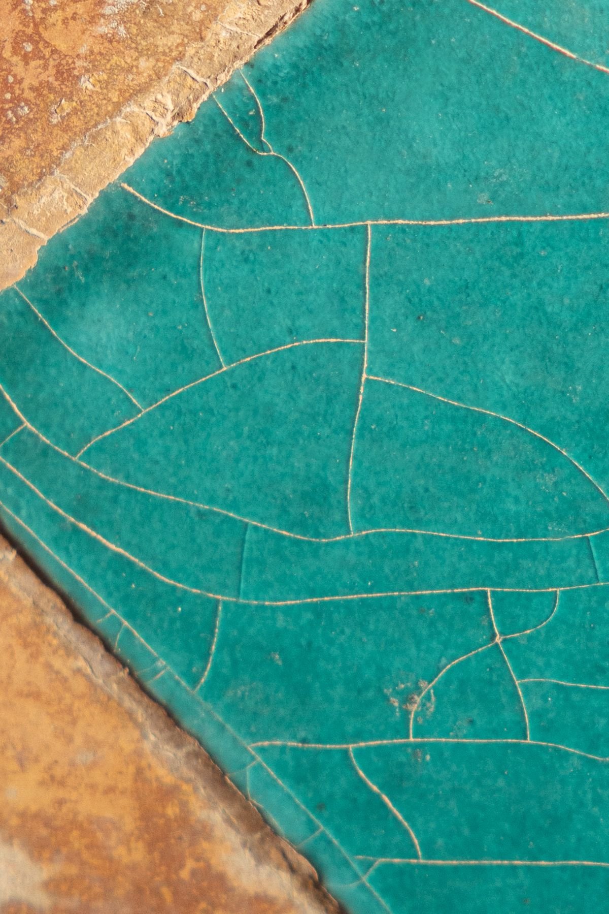 Close-up of a single cracked turquoise tile