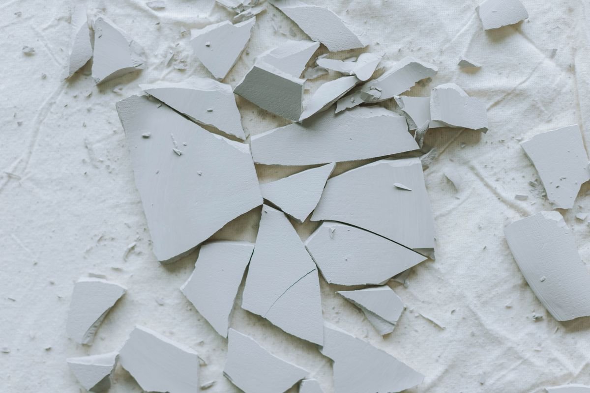 Shards of a broken ceramic tile on a white surface
