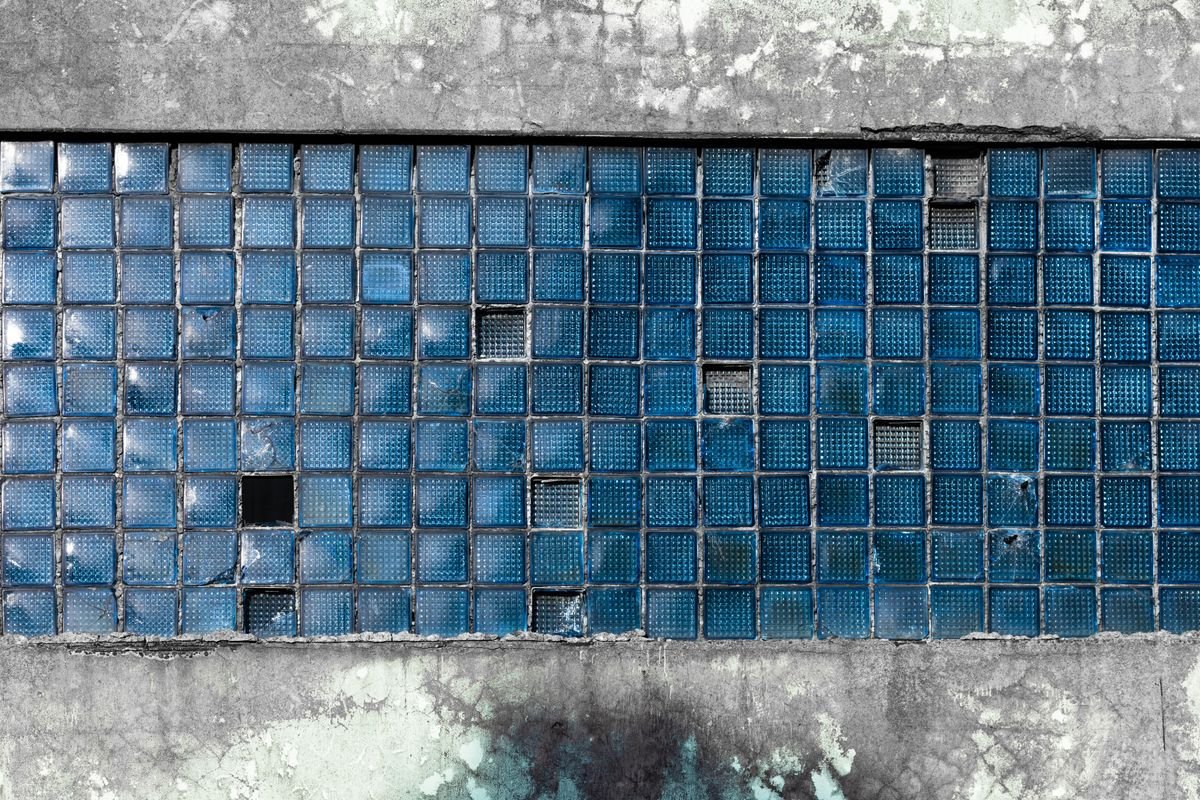 Weathered blue glass wall tiles with cracks and wear