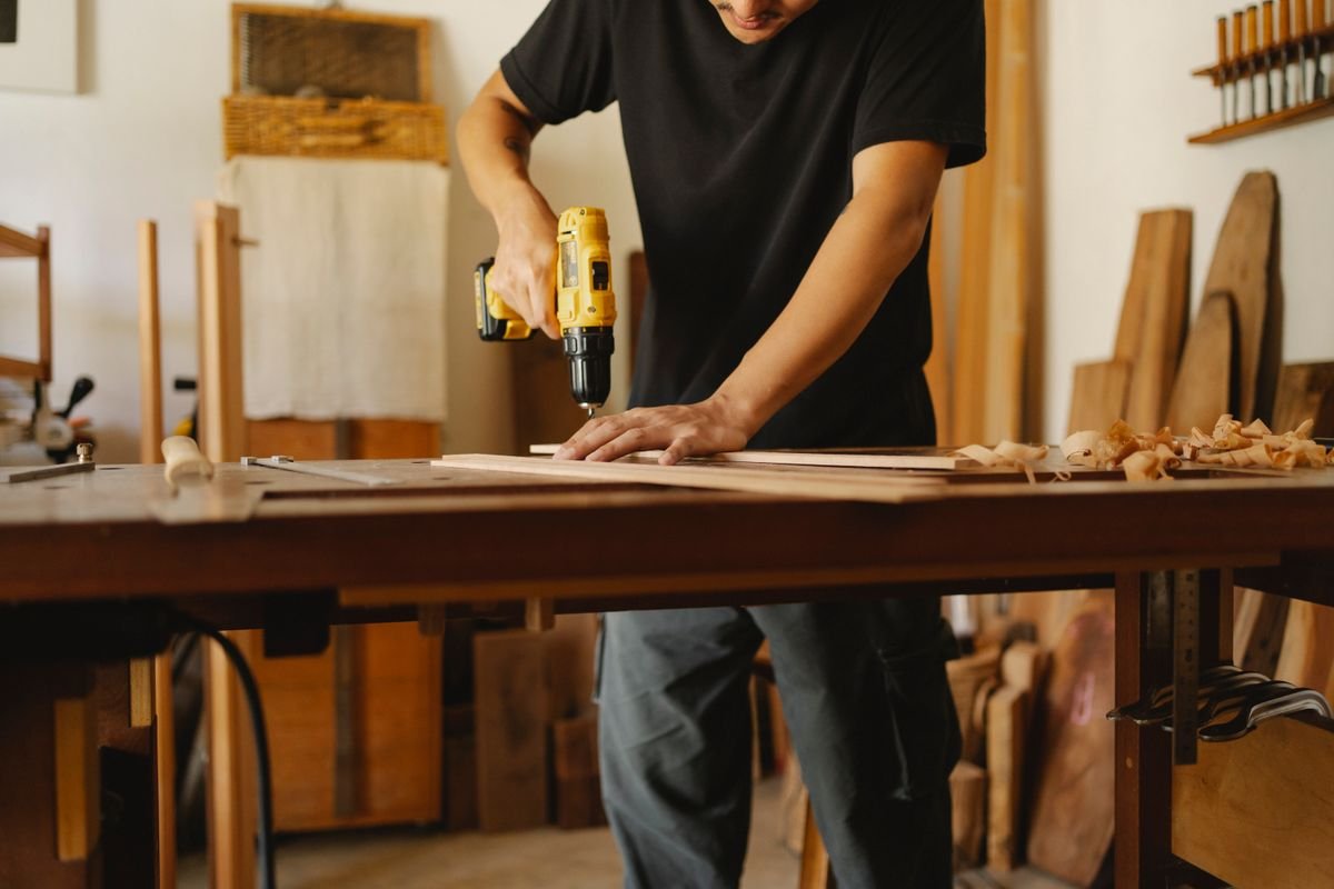 Carpenter drilling a wooden plank in a workshop