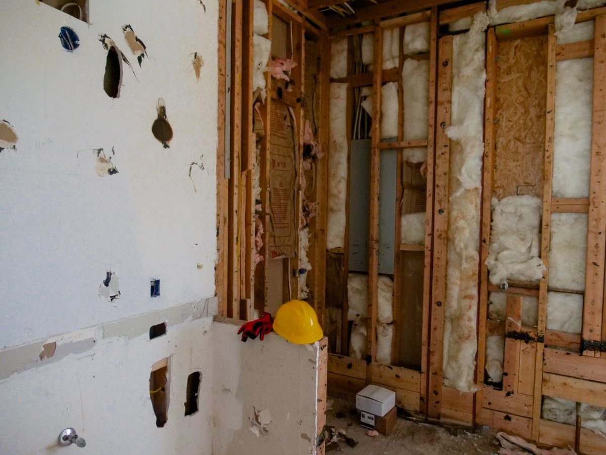 Demolished interior wall showing exposed studs and insulation before repair