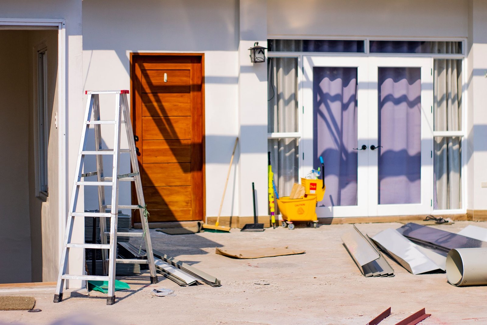 Renovation site with a ladder and materials outside a property entrance