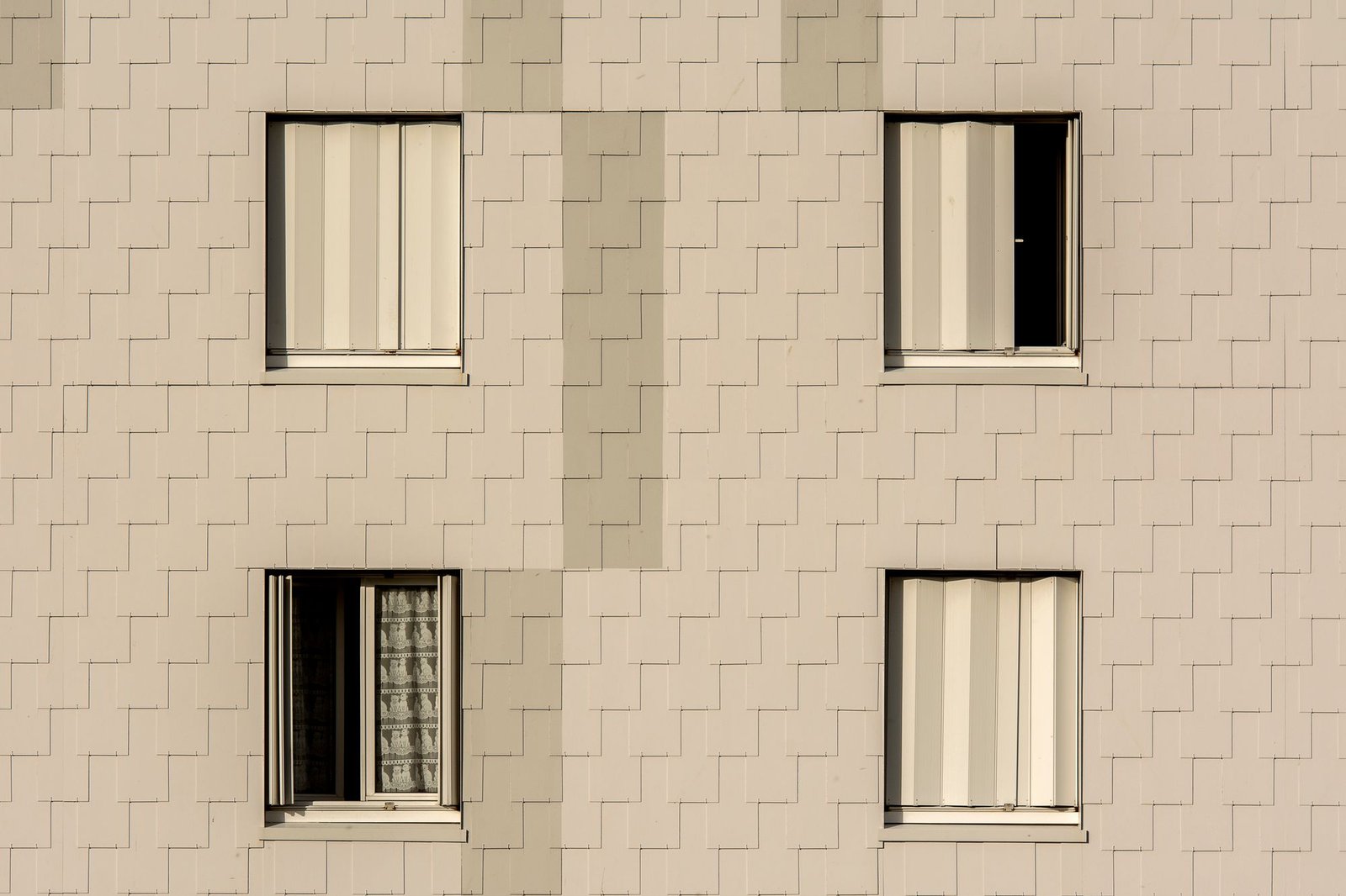 Modern apartment building facade with symmetrical windows and beige cladding