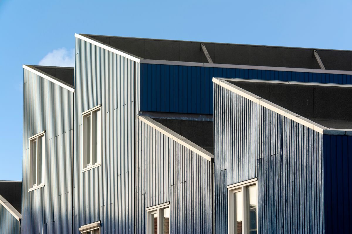 Contemporary geometric building facade with large windows under a clear blue sky