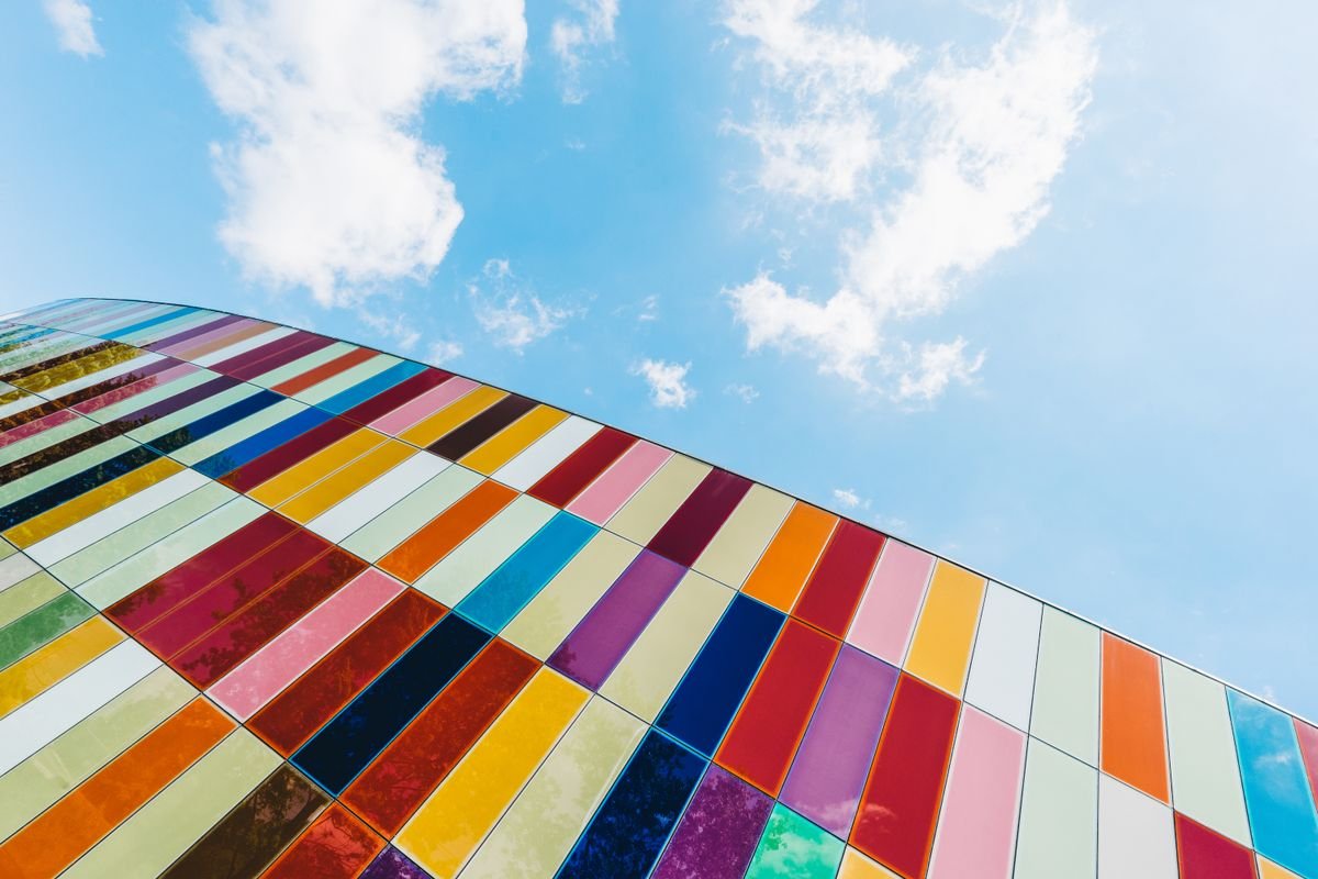 Colourful glass panel facade of a modern building against a blue sky