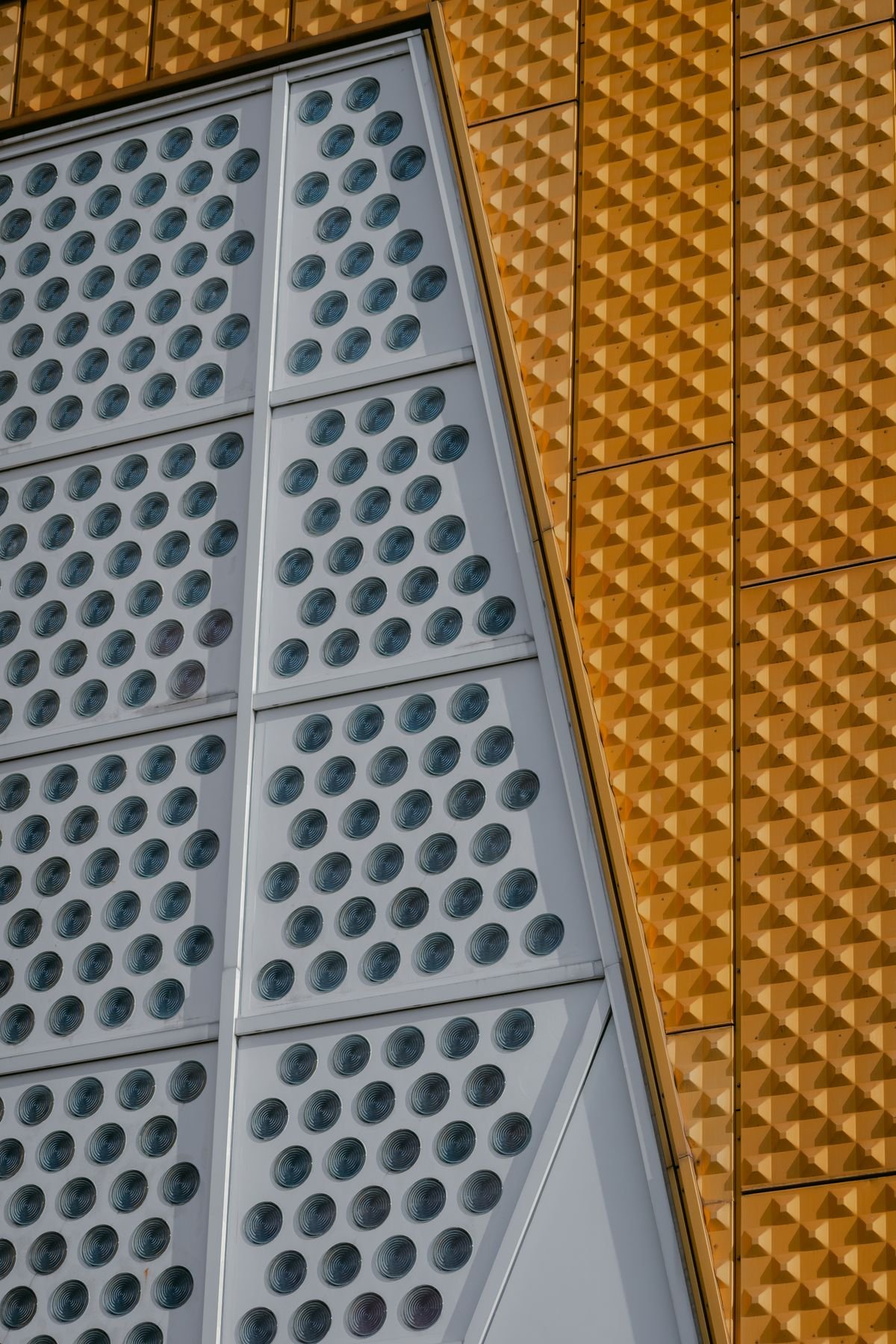 Close-up of a contemporary building facade in grey and orange with textured geometric panels