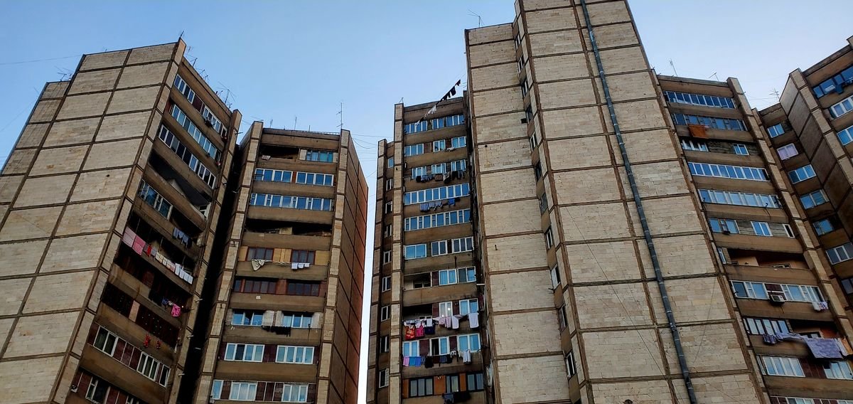 Tall concrete residential towers seen from below against a blue sky