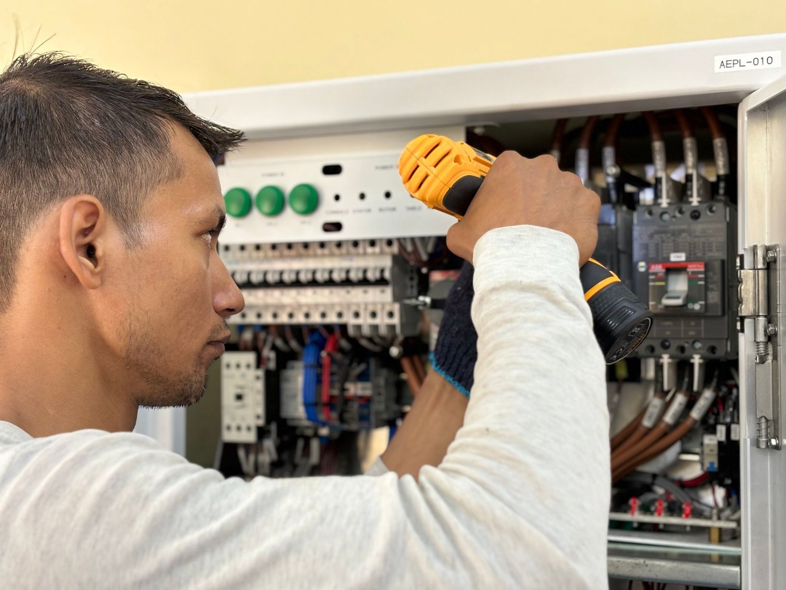Professional using a drill to install equipment in a commercial circuit breaker panel