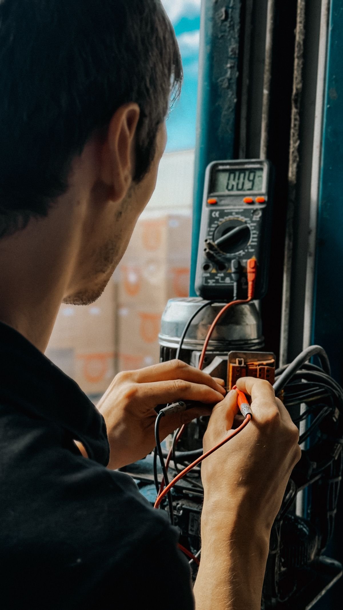 Technician using a multimeter to test electrical equipment on site