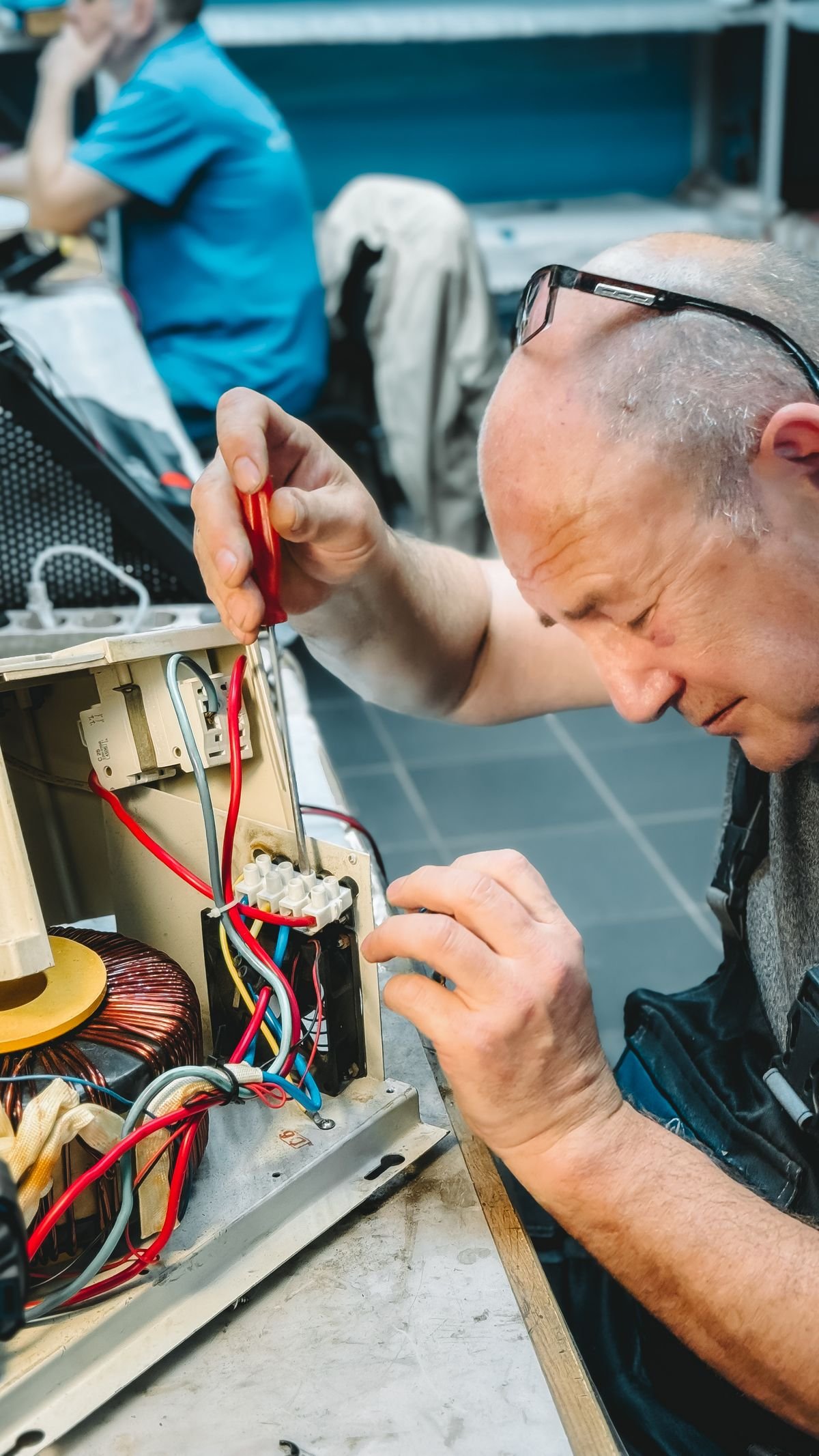 Technician repairing wiring inside an electrical equipment panel