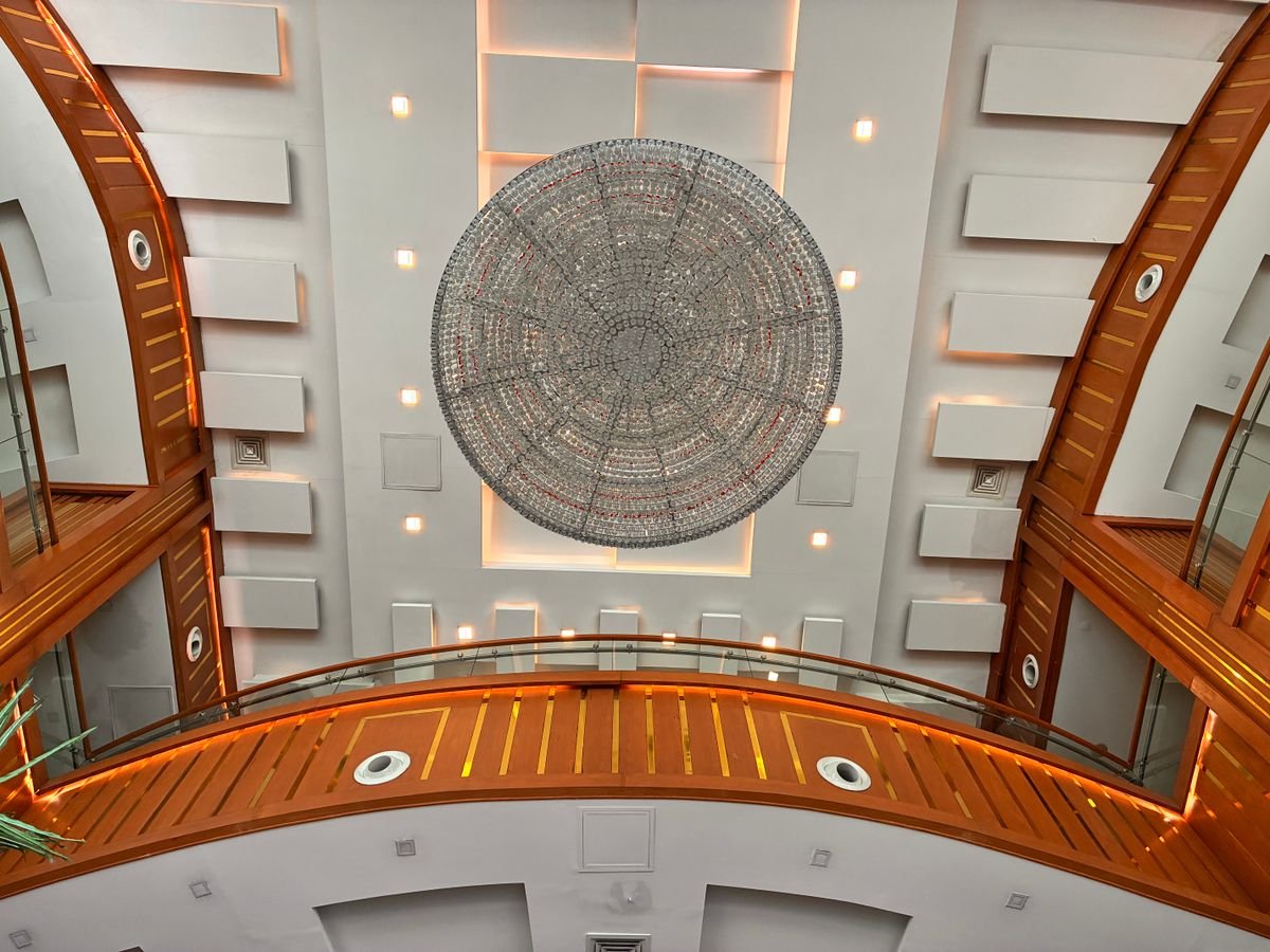 Atrium with a coffered ceiling, circular feature panel, and timber-lined balcony