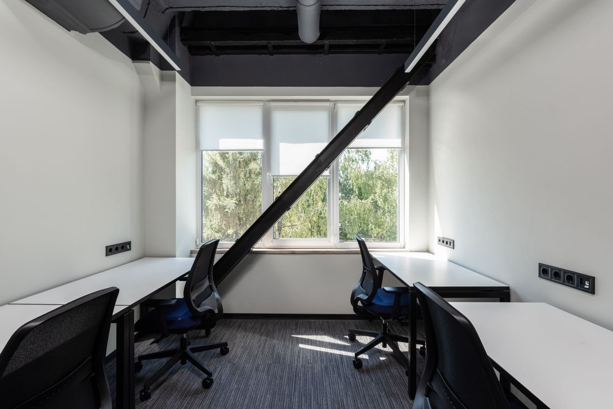 Bright office interior with white workstations, task chairs, and a large window