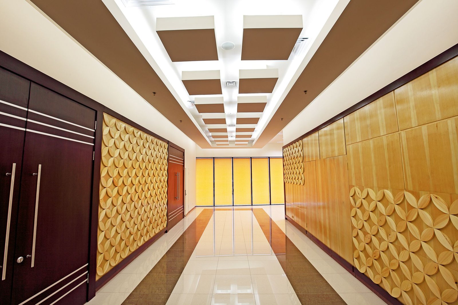 Long corridor with a glossy polished marble floor, gold decorative wall panels, and a coffered ceiling