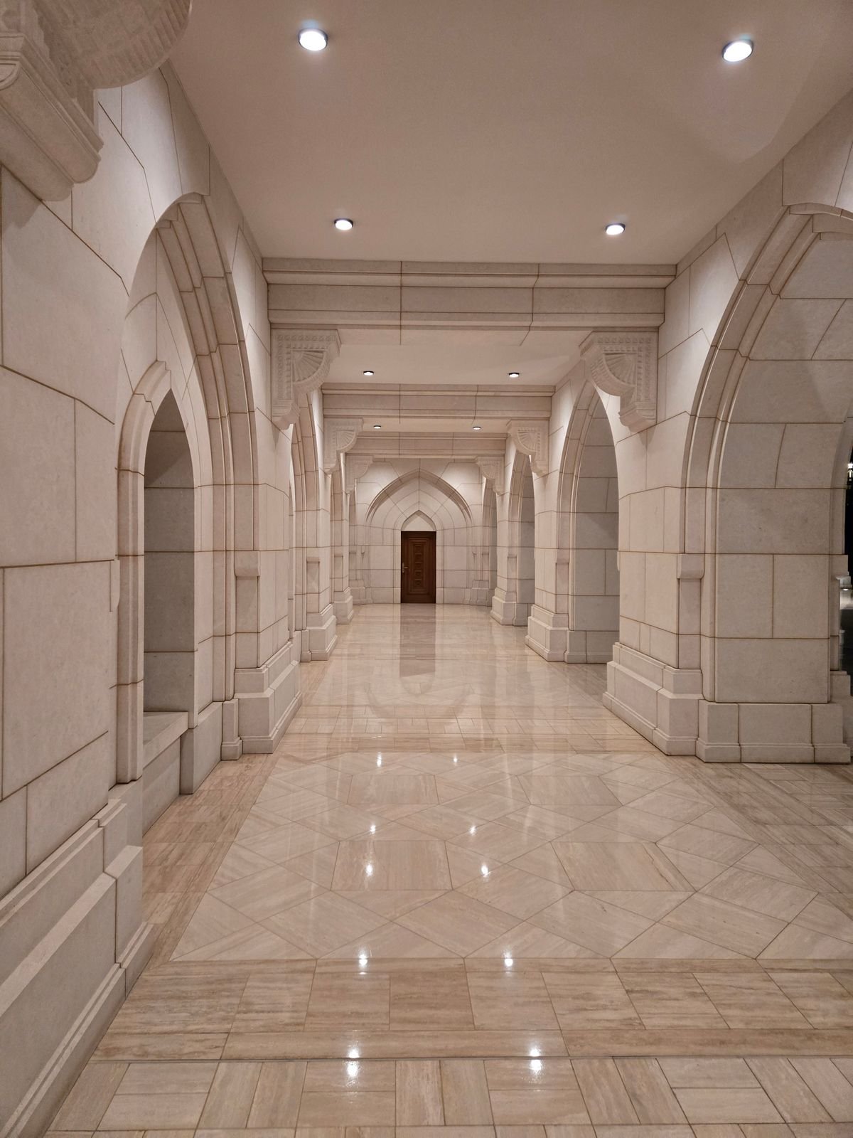 Grand arched corridor with a polished stone floor reflecting recessed lights
