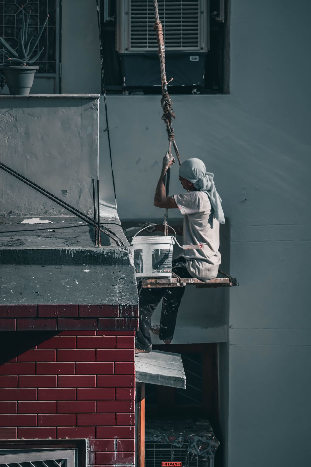 Worker on a scaffold painting the exterior wall of a building