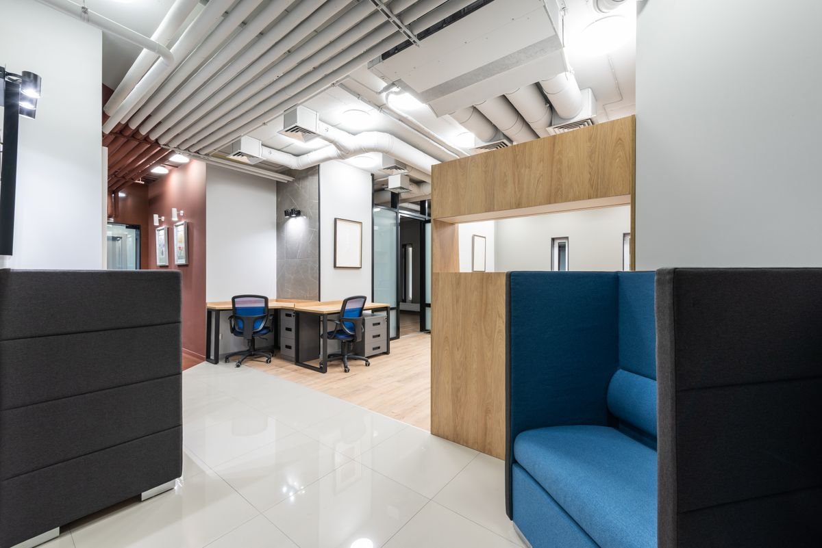 Bright office area with clean painted walls, a blue seat, and dark cabinetry