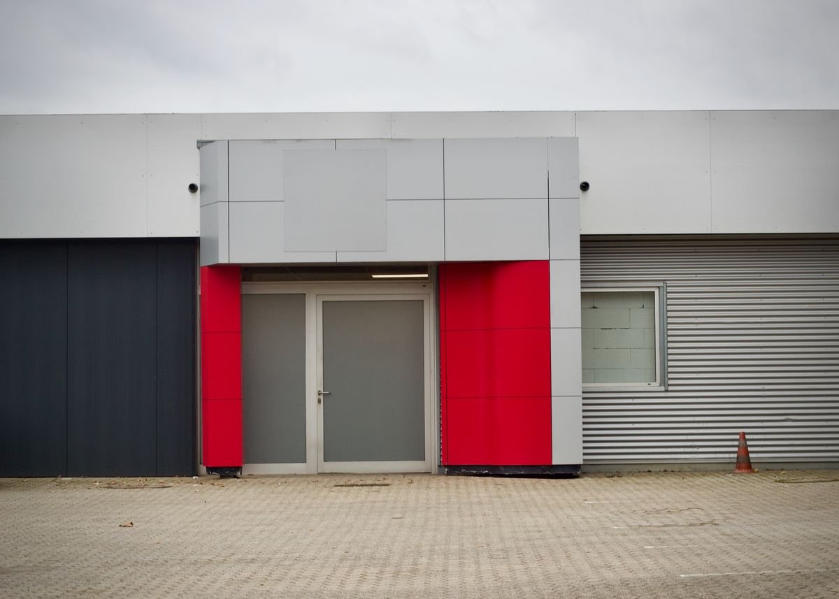 Modern industrial building entrance with red accents and metal cladding