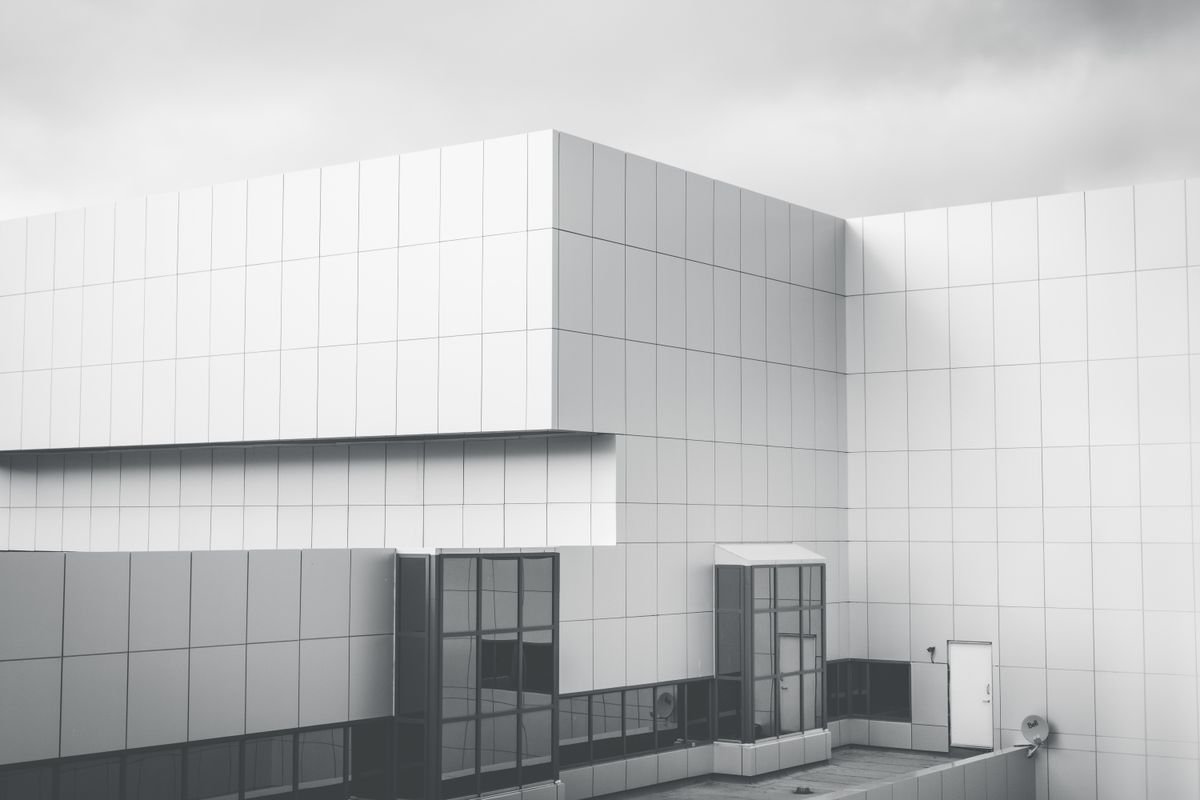 Minimalist white panel facade of a modern building against a cloudy sky