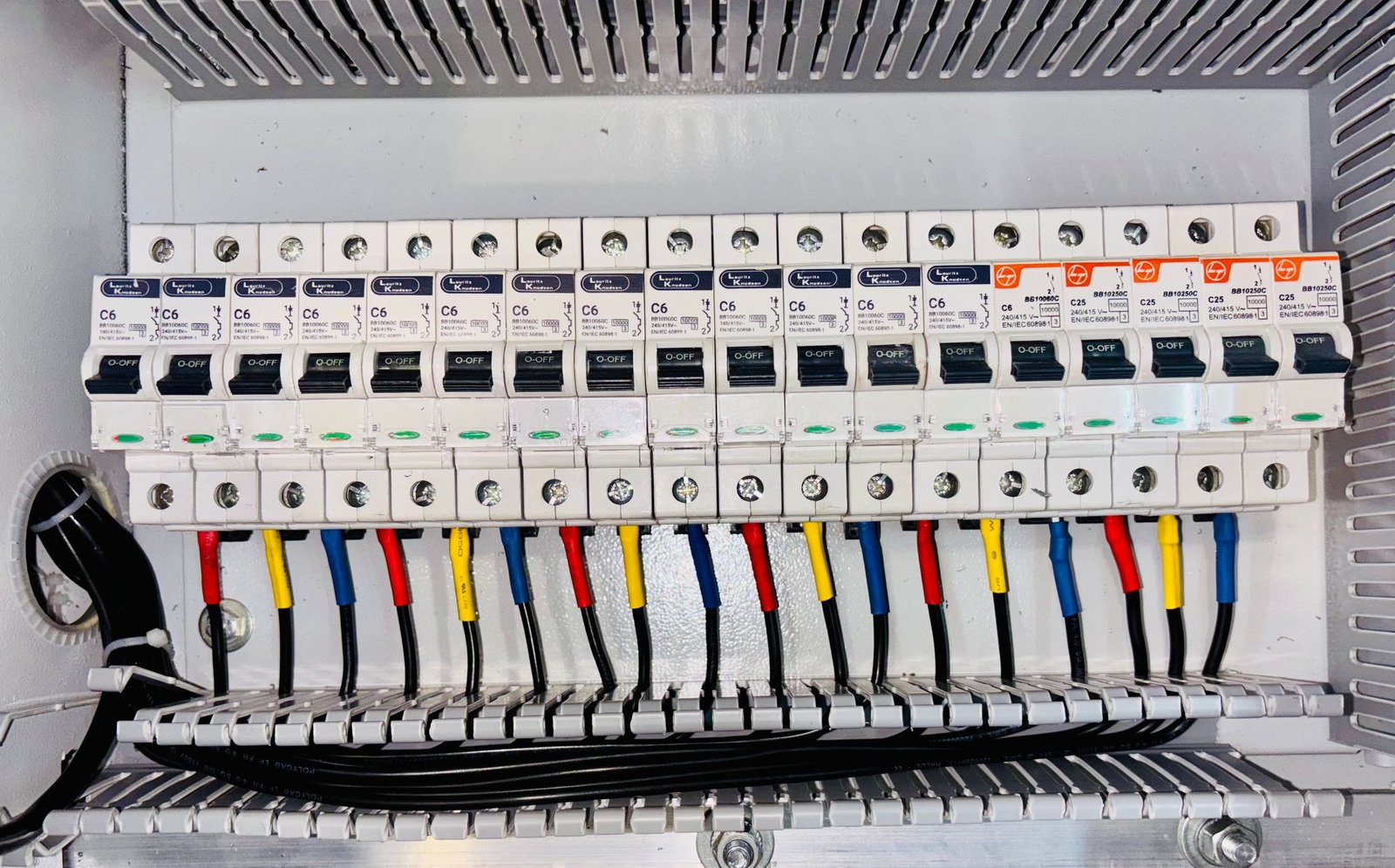 Close-up of an organized distribution board with color-coded circuit breaker wiring