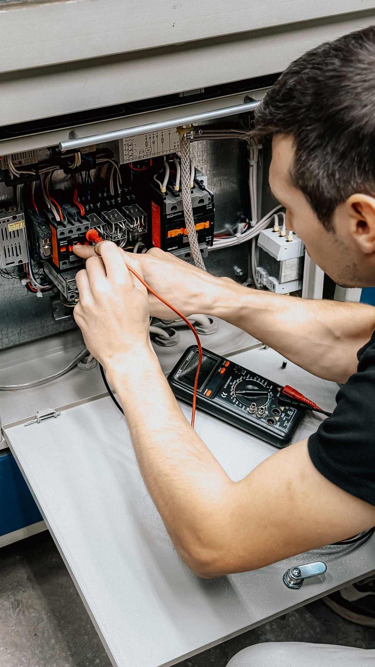 Electrician using a multimeter to test a distribution board circuit